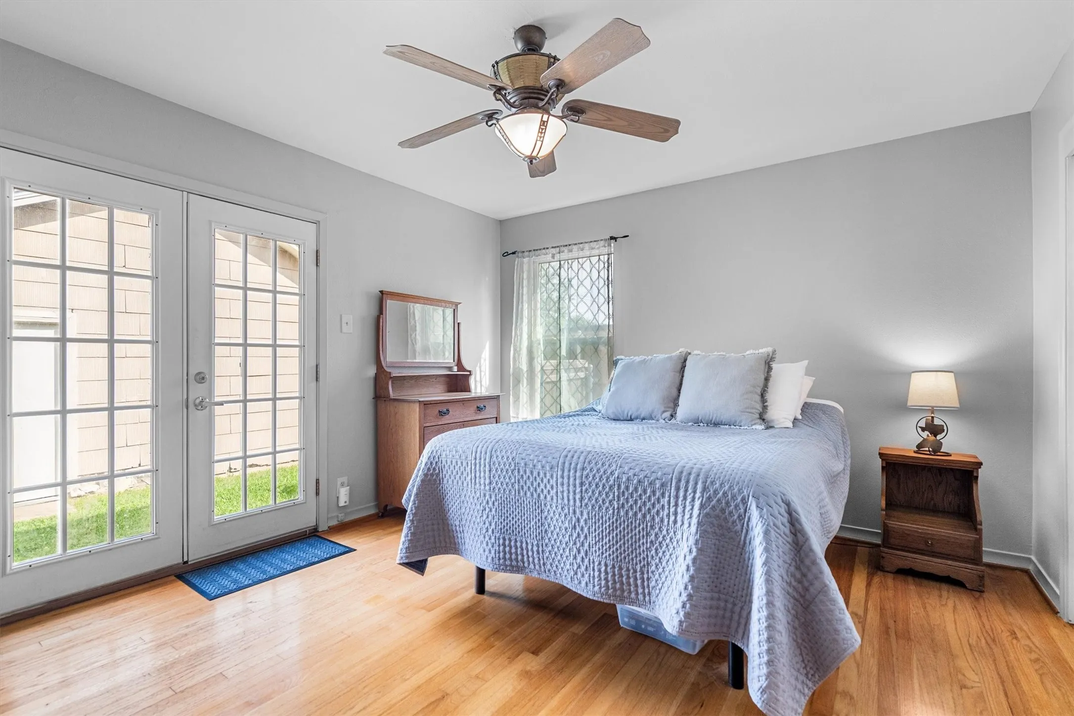 Bedroom featuring hardwood flooring, a ceiling fan with light fixture, light gray walls, and French doors providing outdoor access