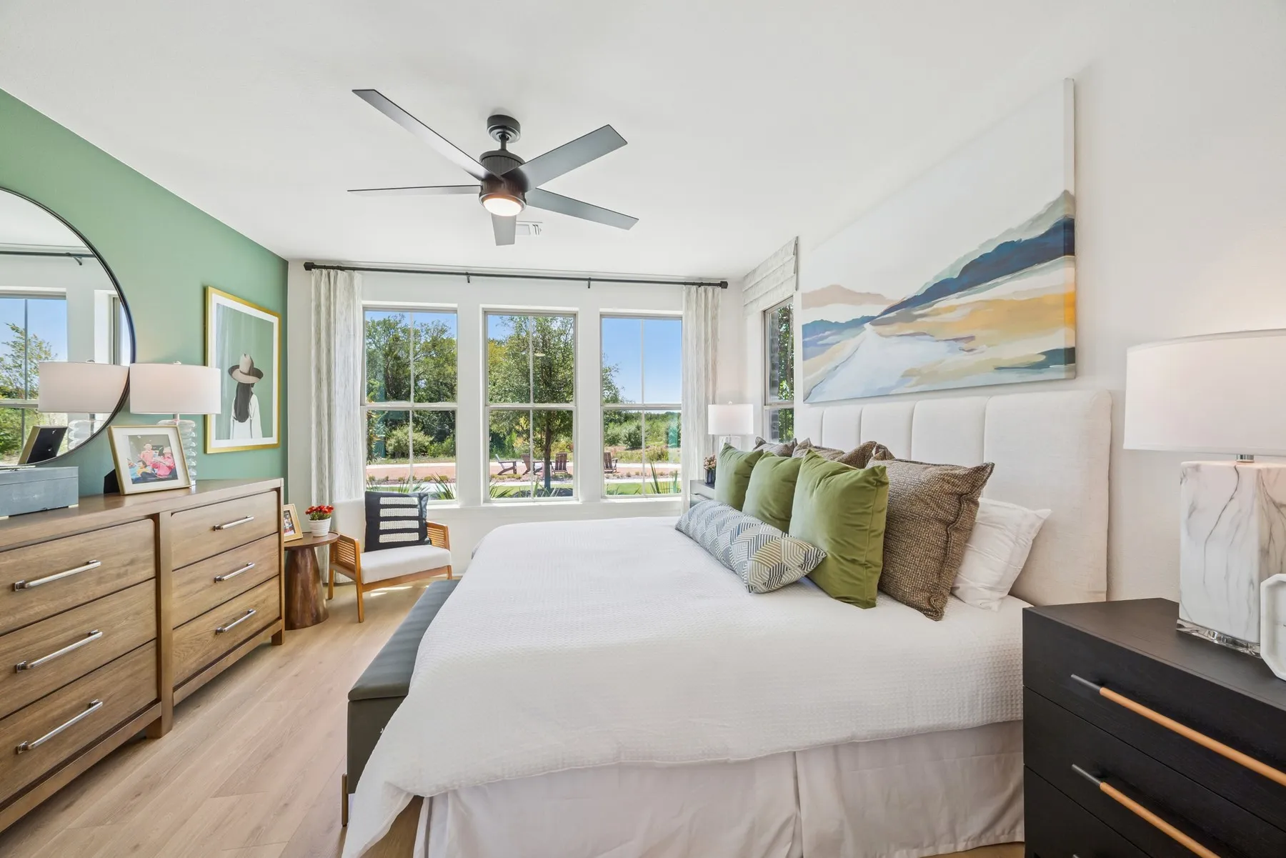 Spacious room with light wood-finish flooring, a contemporary ceiling fan, and large windows providing abundant natural light