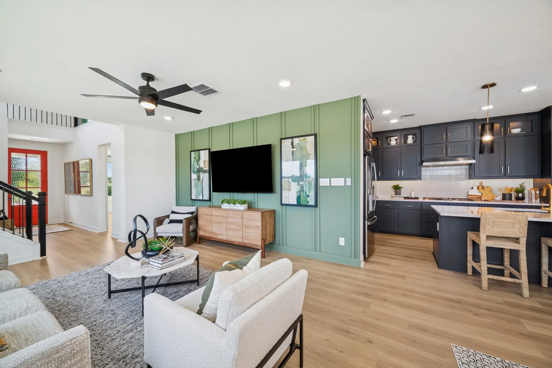 Open-concept living area featuring wood-finish flooring, a contemporary ceiling fan, and a green accent wall with vertical paneling