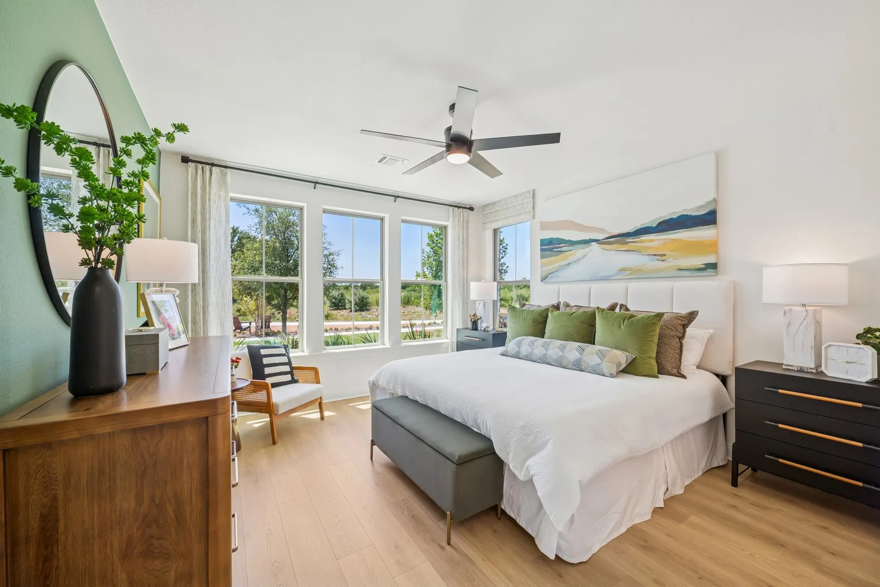 Bedroom featuring light wood-finish flooring, a contemporary ceiling fan, and multiple large windows with white trim