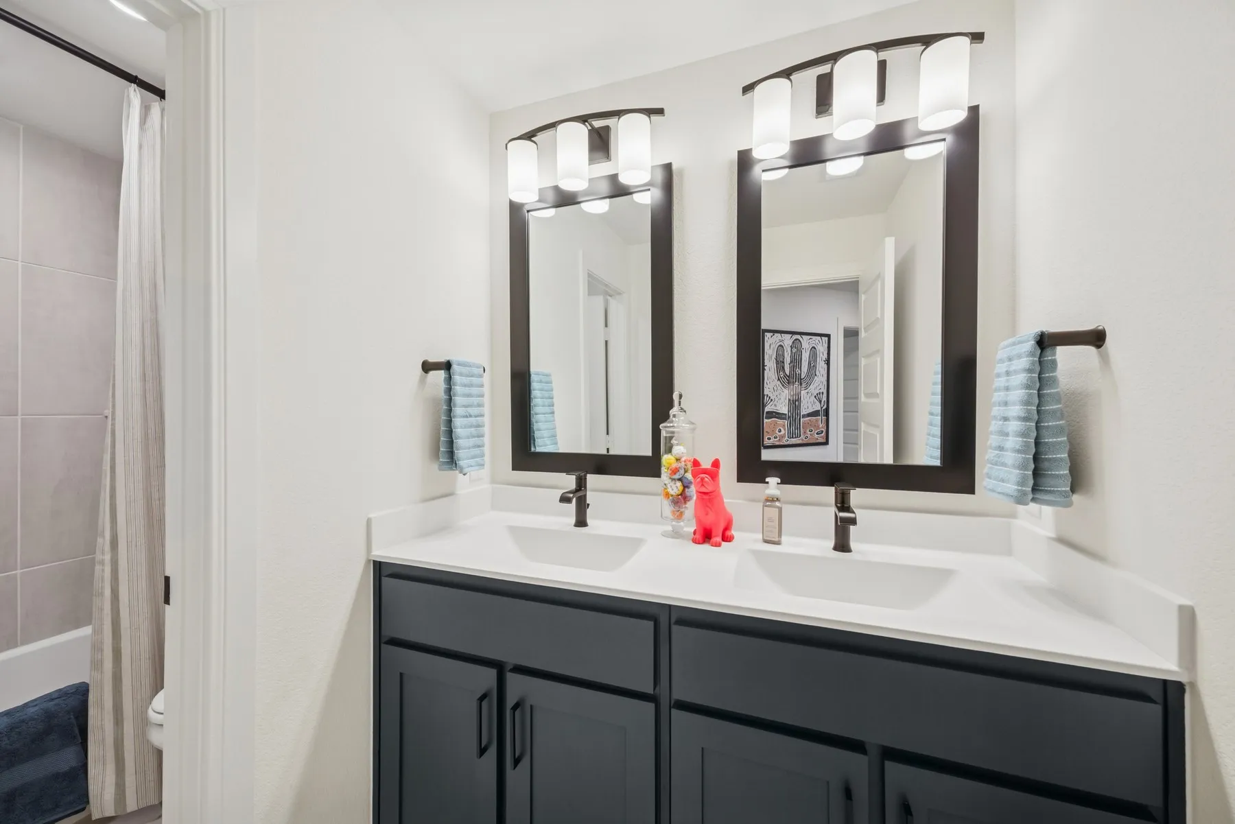 Dual vanity with white countertops and dark cabinetry, featuring two mirrors with integrated lighting
