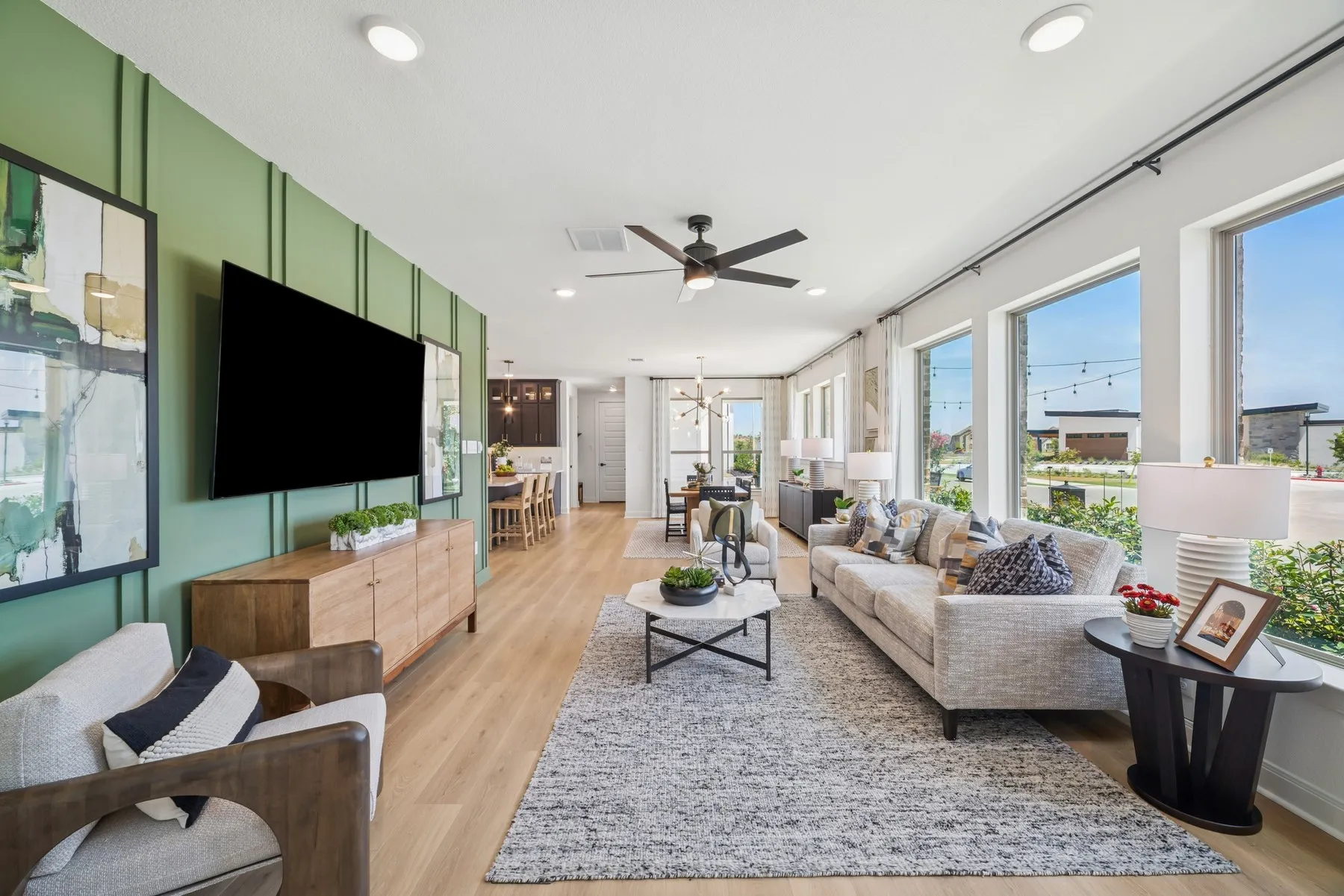 Open-concept living space with light wood-finish flooring, recessed ceiling lighting, and a modern ceiling fan