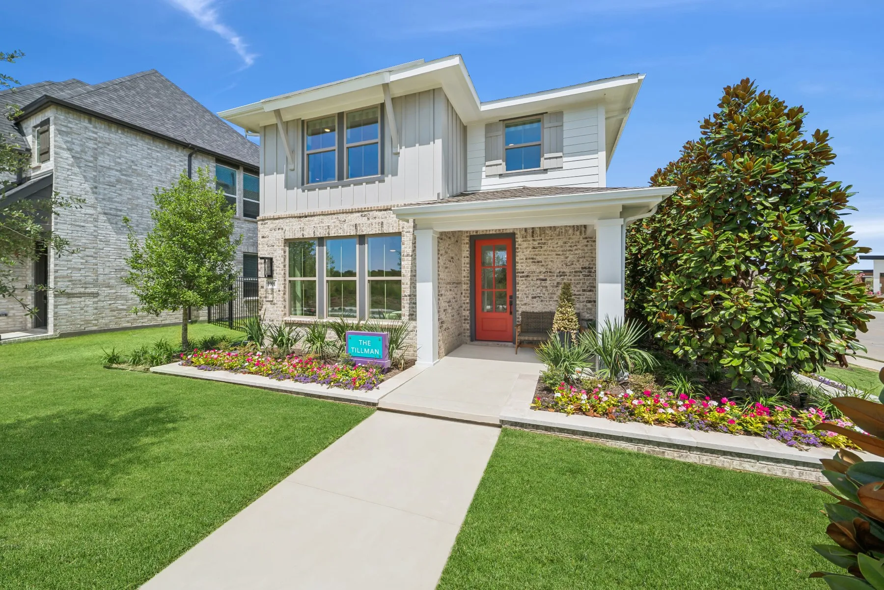 Contemporary two-story residence featuring a red entry door, brick and siding facade, and a covered porch
