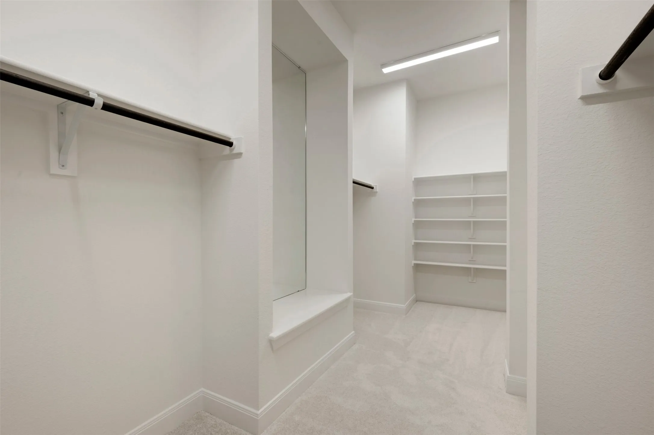 Spacious walk-in closet with carpet flooring, built-in shelving, and multiple clothing rods