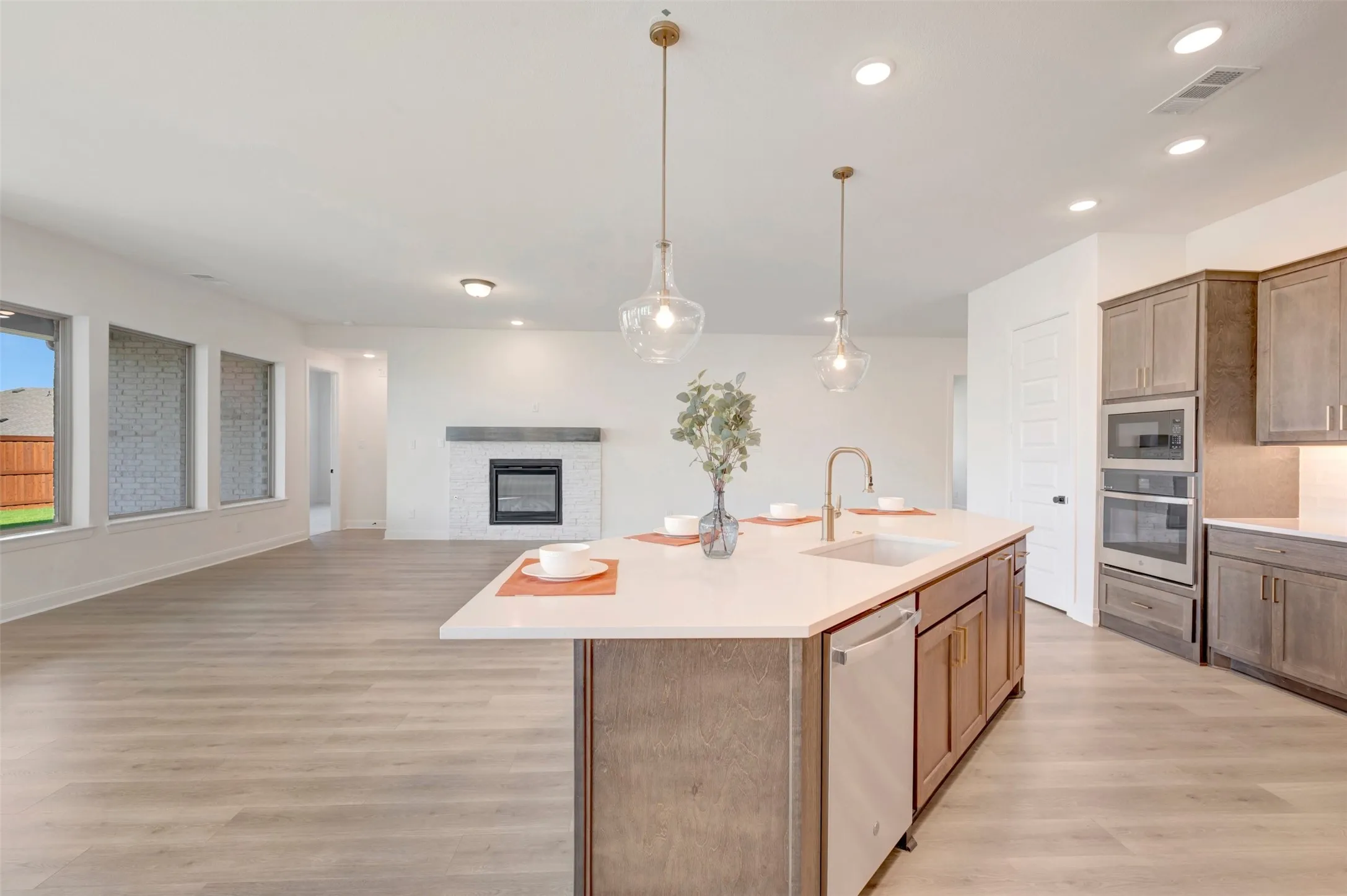 Expansive kitchen island with a built-in sink, pendant lighting, and light-toned cabinetry