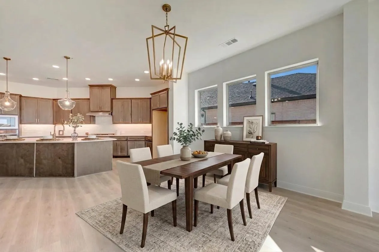 Open-concept living space with wood-finish flooring, a kitchen featuring an island and pendant lighting, and a dining area illuminated by a geometric chandelier and multiple windows