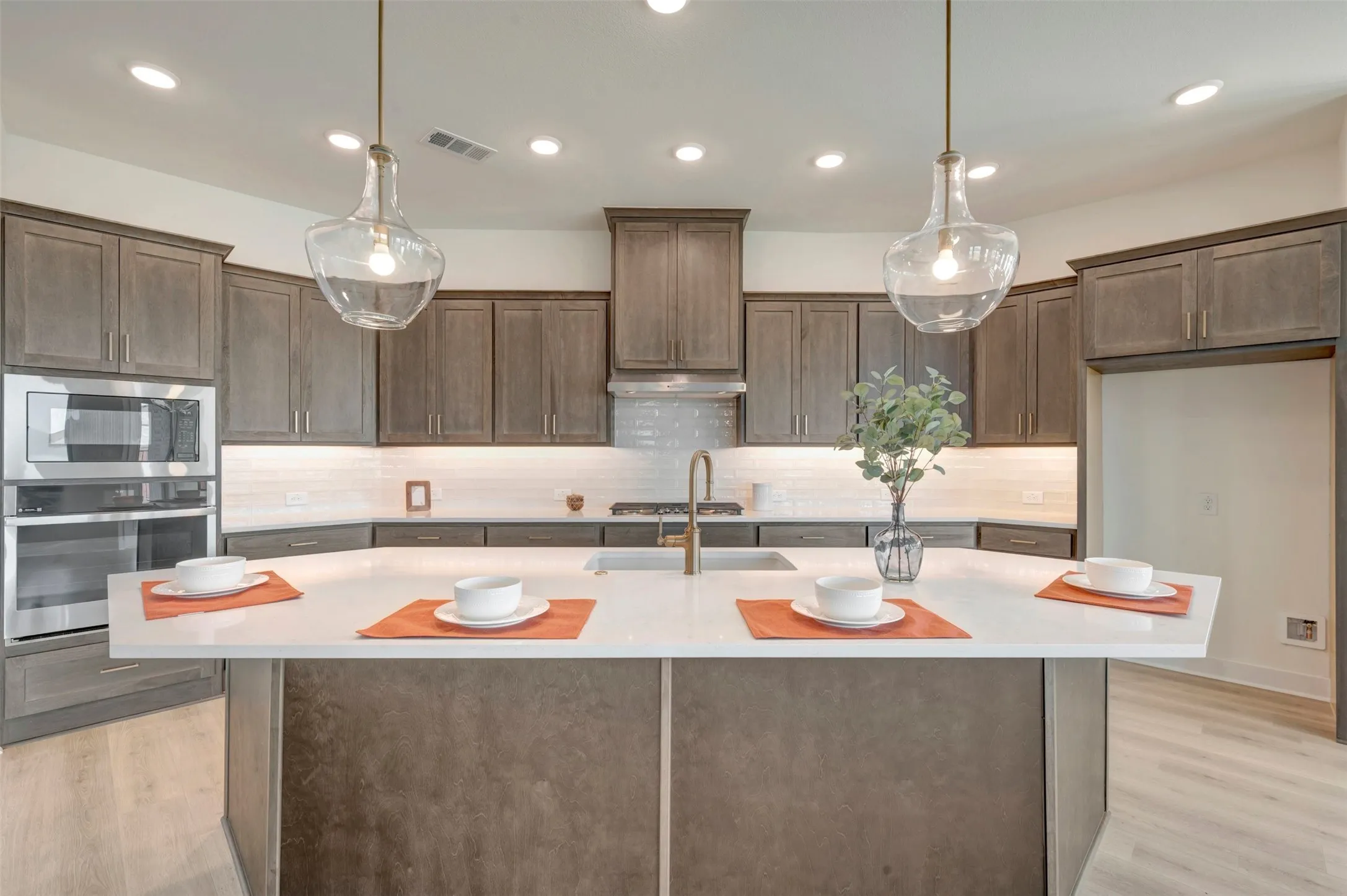 Kitchen featuring a large central island with a white countertop, recessed lighting, two pendant lights, and stainless steel appliances