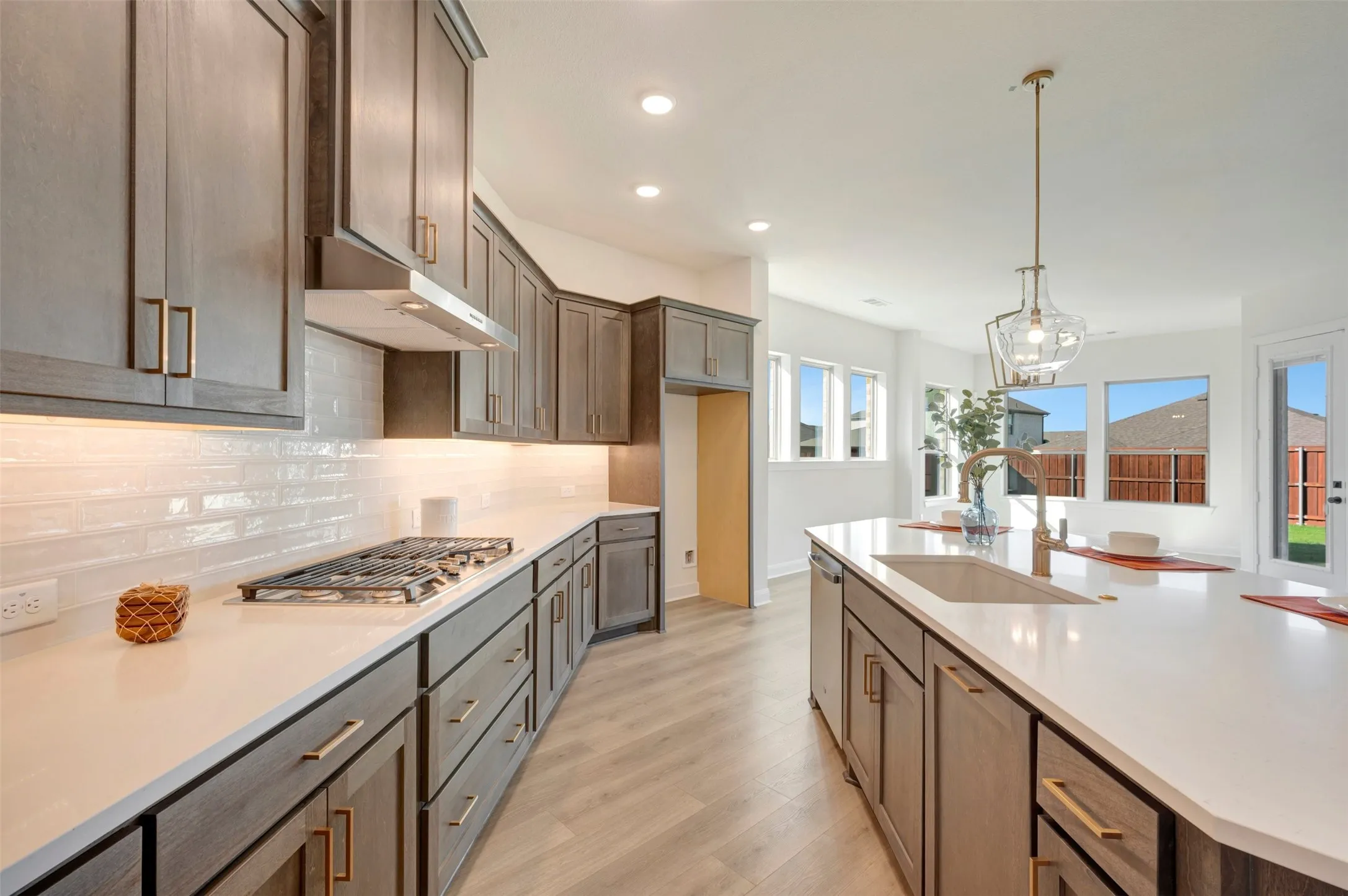 Kitchen featuring wood-finish cabinetry, white countertops, a tiled backsplash, and recessed lighting