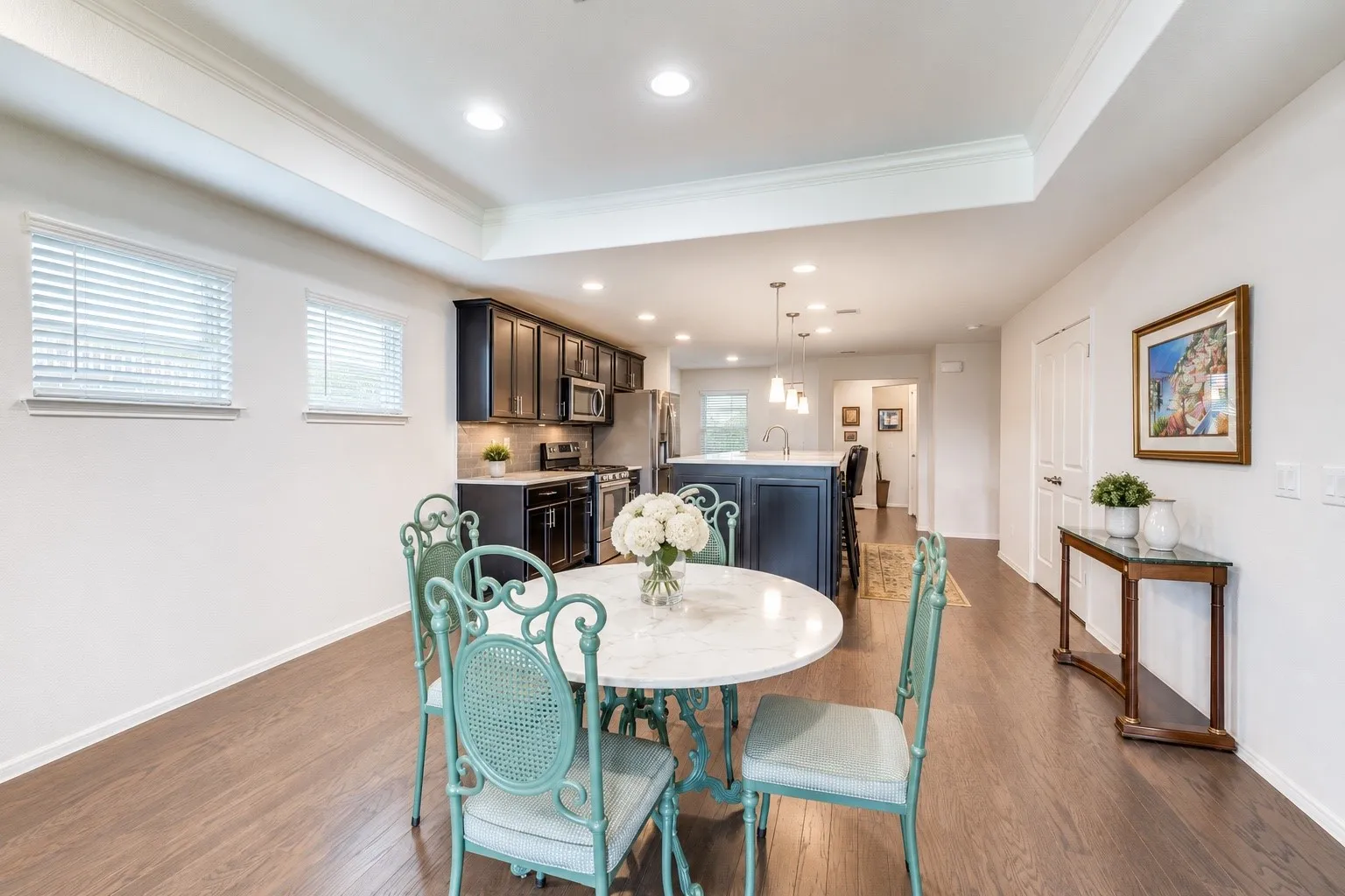 Open concept living space featuring wood-finish flooring, a tray ceiling, and recessed lighting