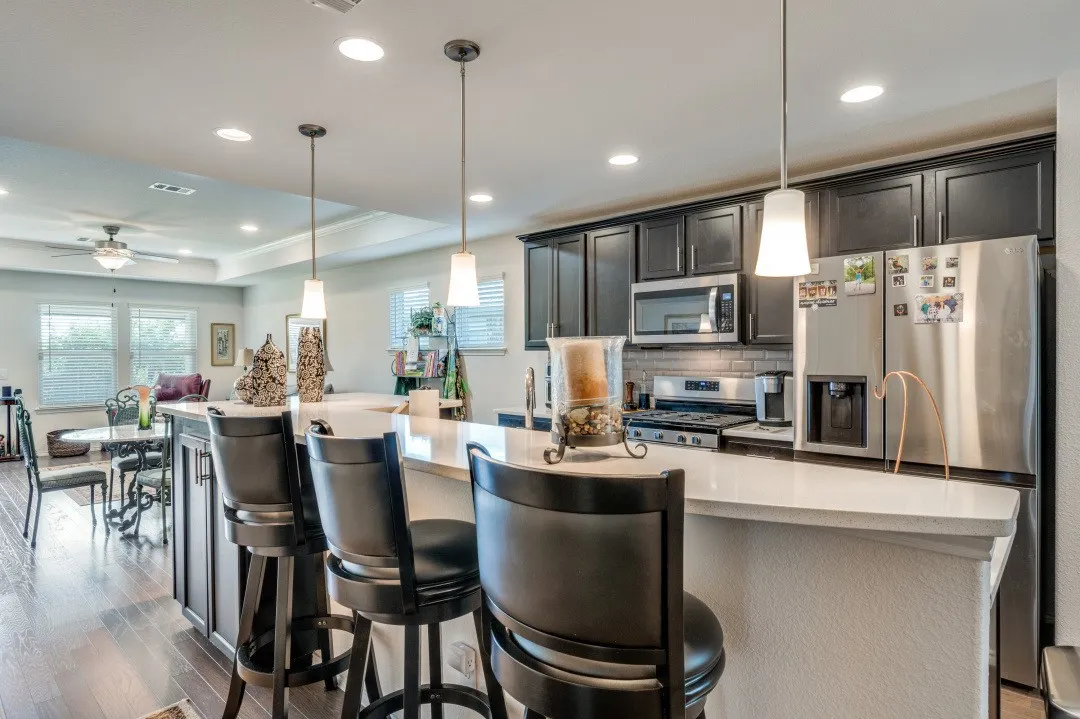 Kitchen featuring a large island with counter seating, dark wood-finish cabinetry, stainless steel appliances, and recessed lighting