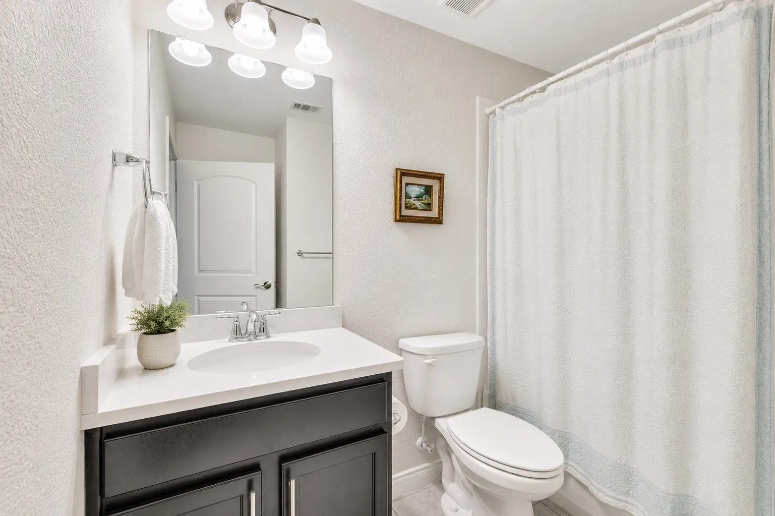 Bathroom featuring a vanity with a white countertop, undermount sink, and dark wood-finish cabinetry