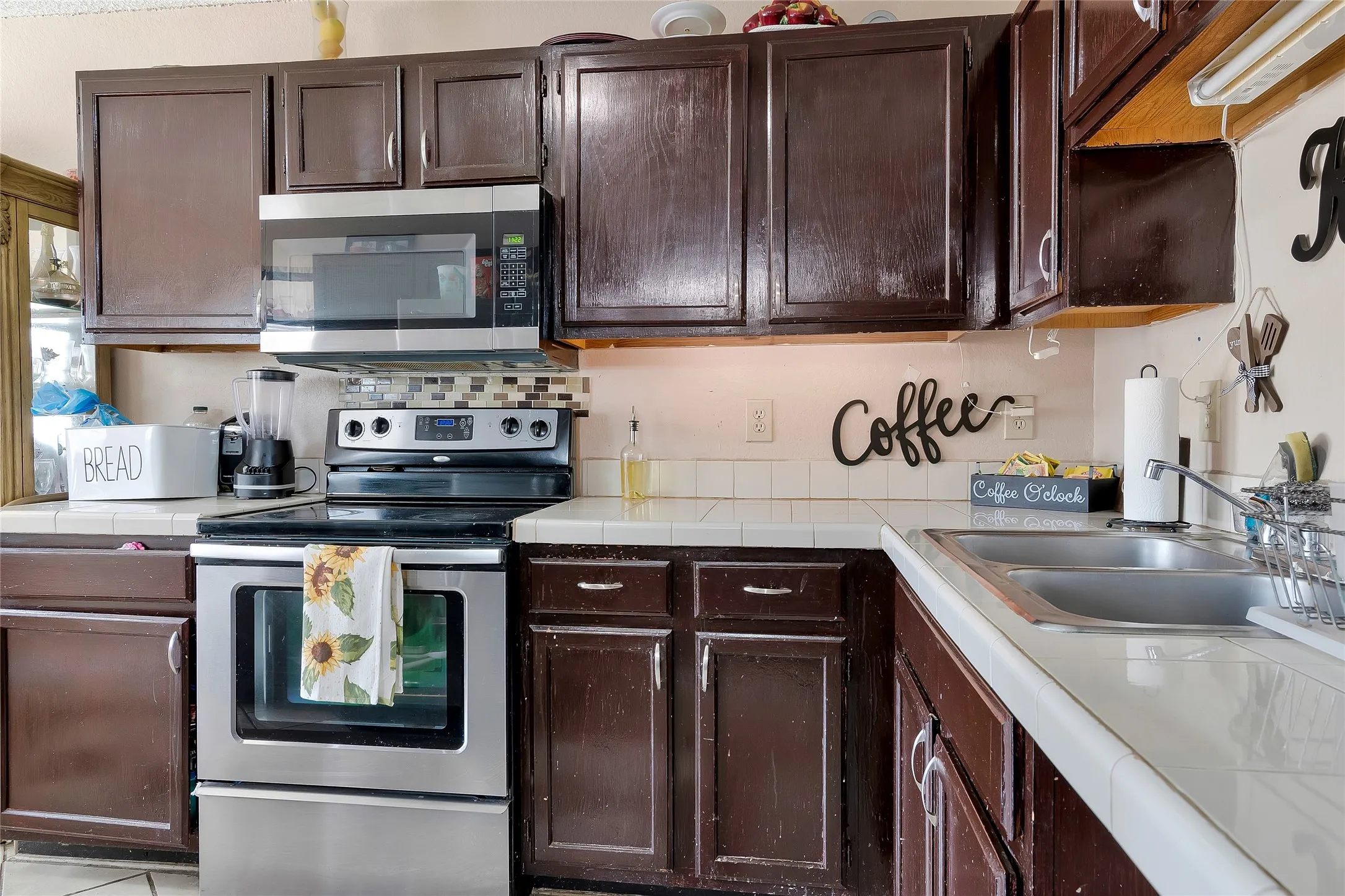 Kitchen with sink, tile countertops, dark brown cabinetry, and stainless steel appliances