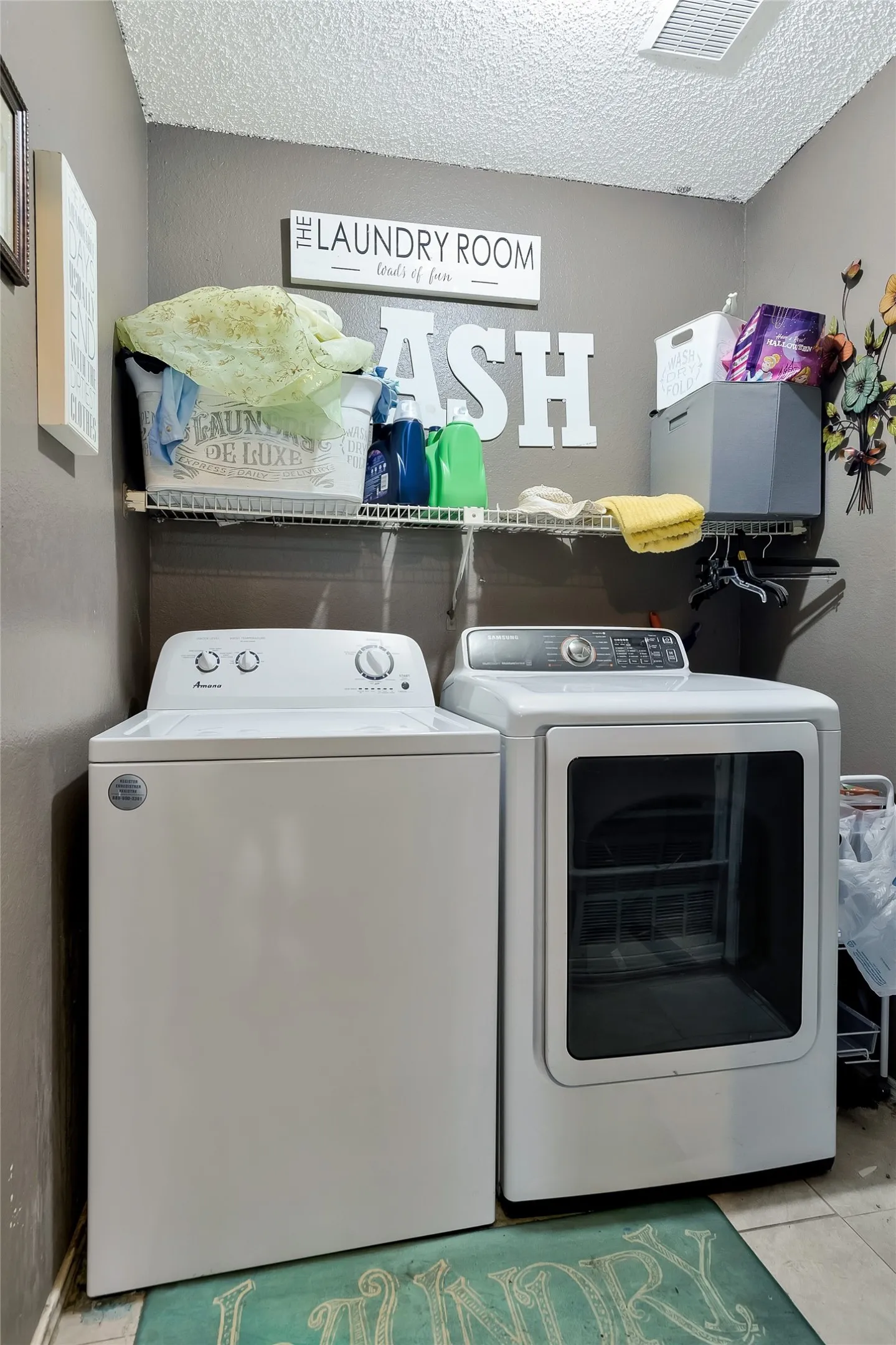 Laundry area with light tile patterned flooring, separate washer and dryer, and a textured ceiling