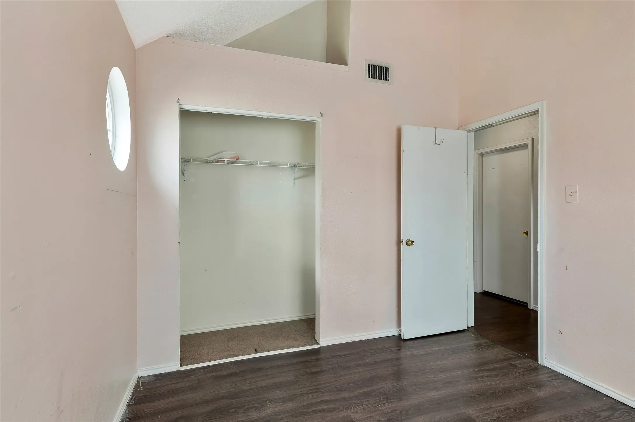 Unfurnished bedroom featuring dark wood-type flooring, a closet, and high vaulted ceiling