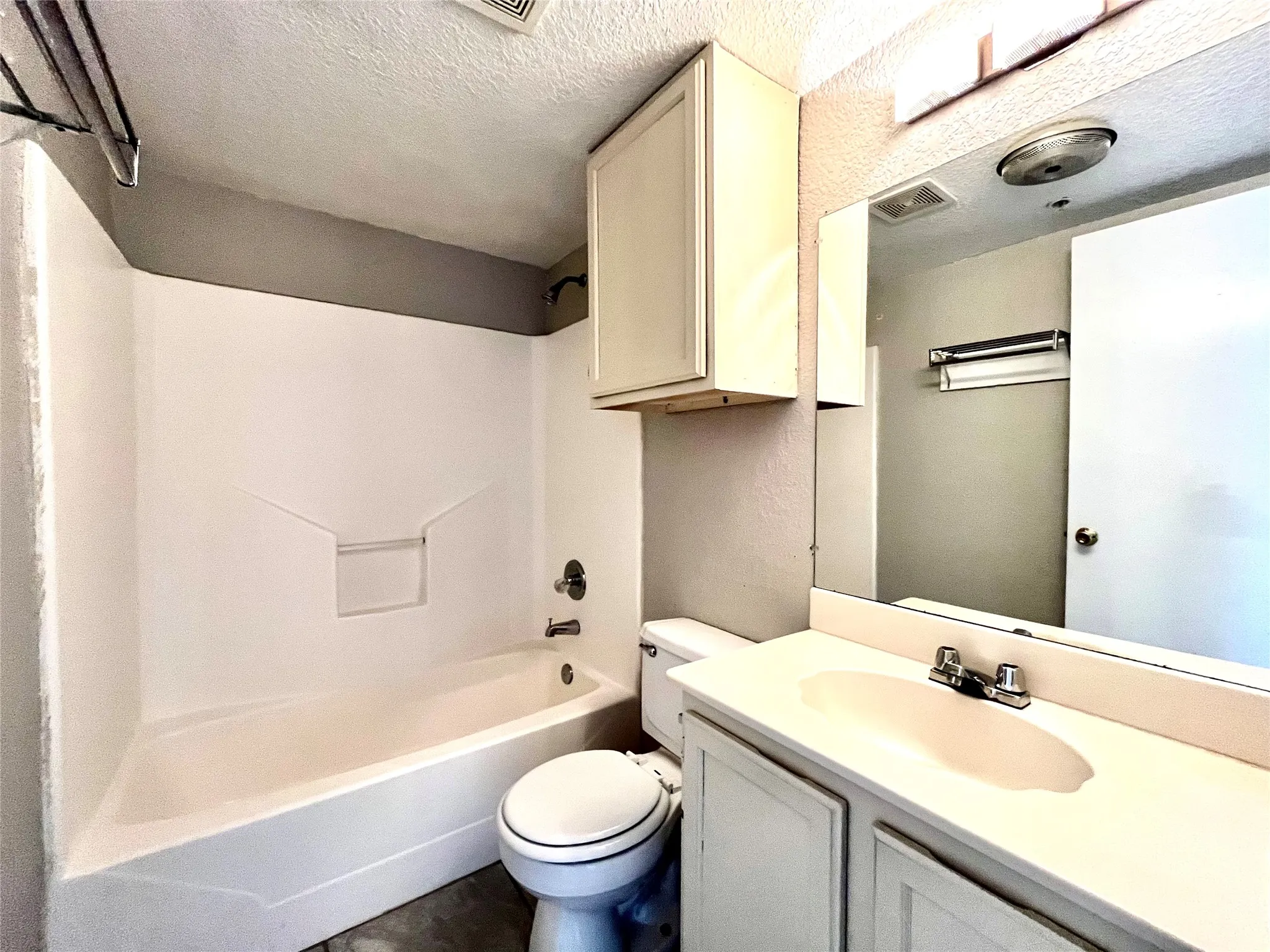 Bright bathroom featuring a large mirror, vanity storage, and a clean tub-to-ceiling tile surround.