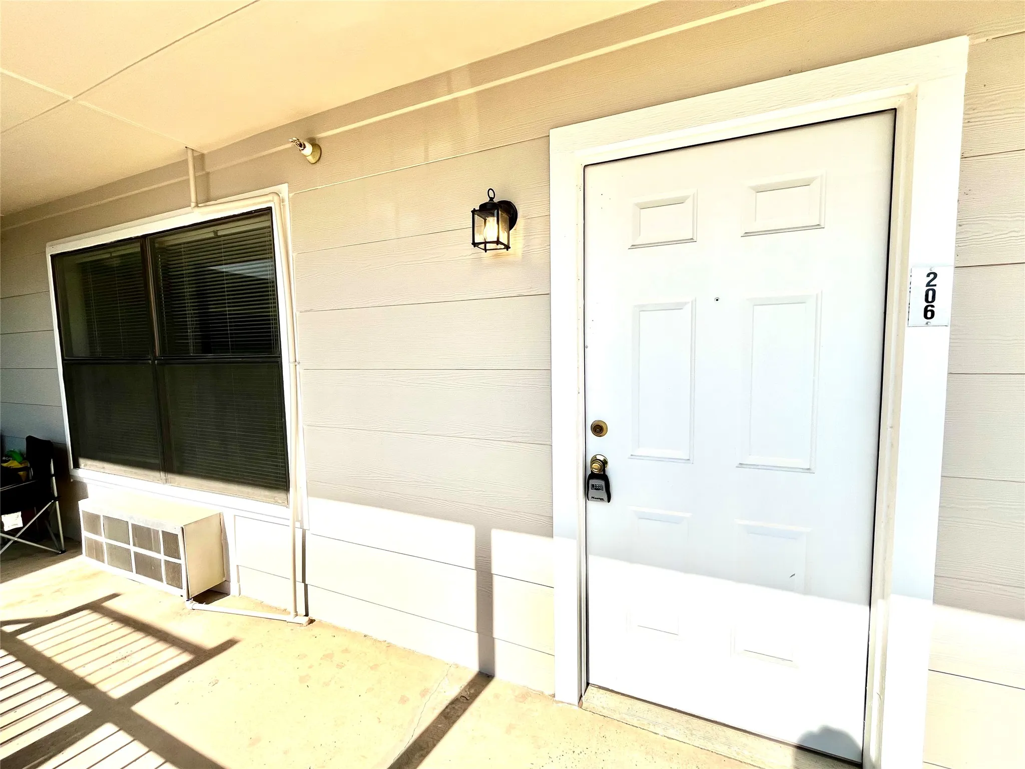 Private unit entrance with clean neutral siding and a well-lit covered walkway.