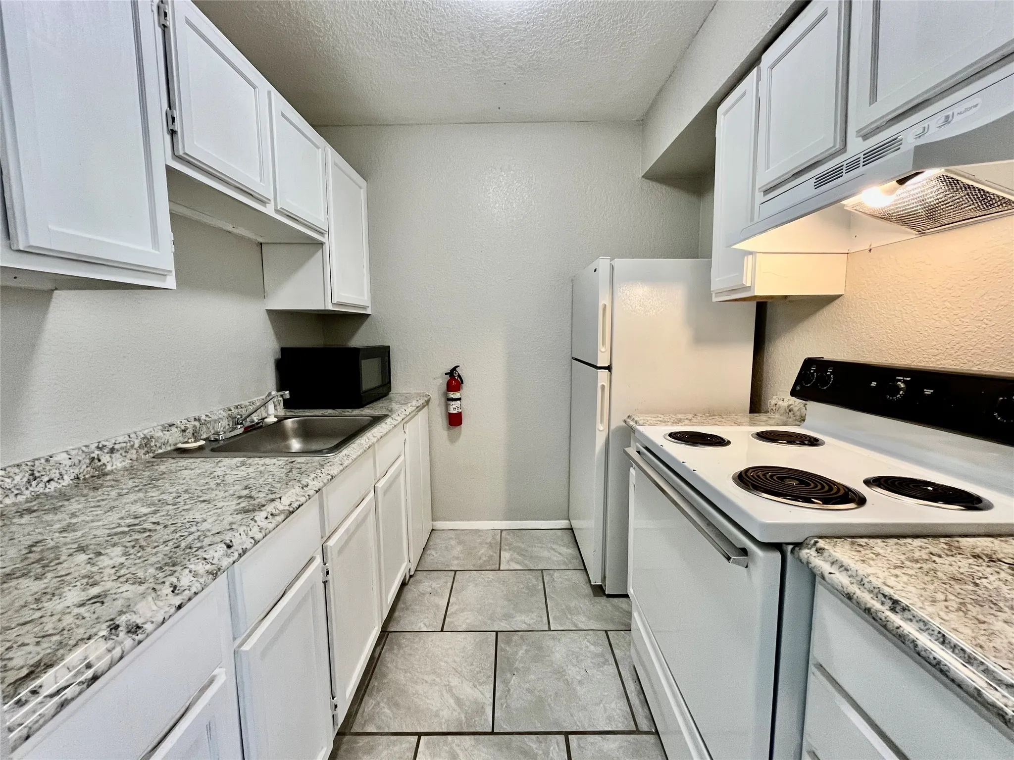 Modernized kitchen boasting sleek countertops, white cabinetry.