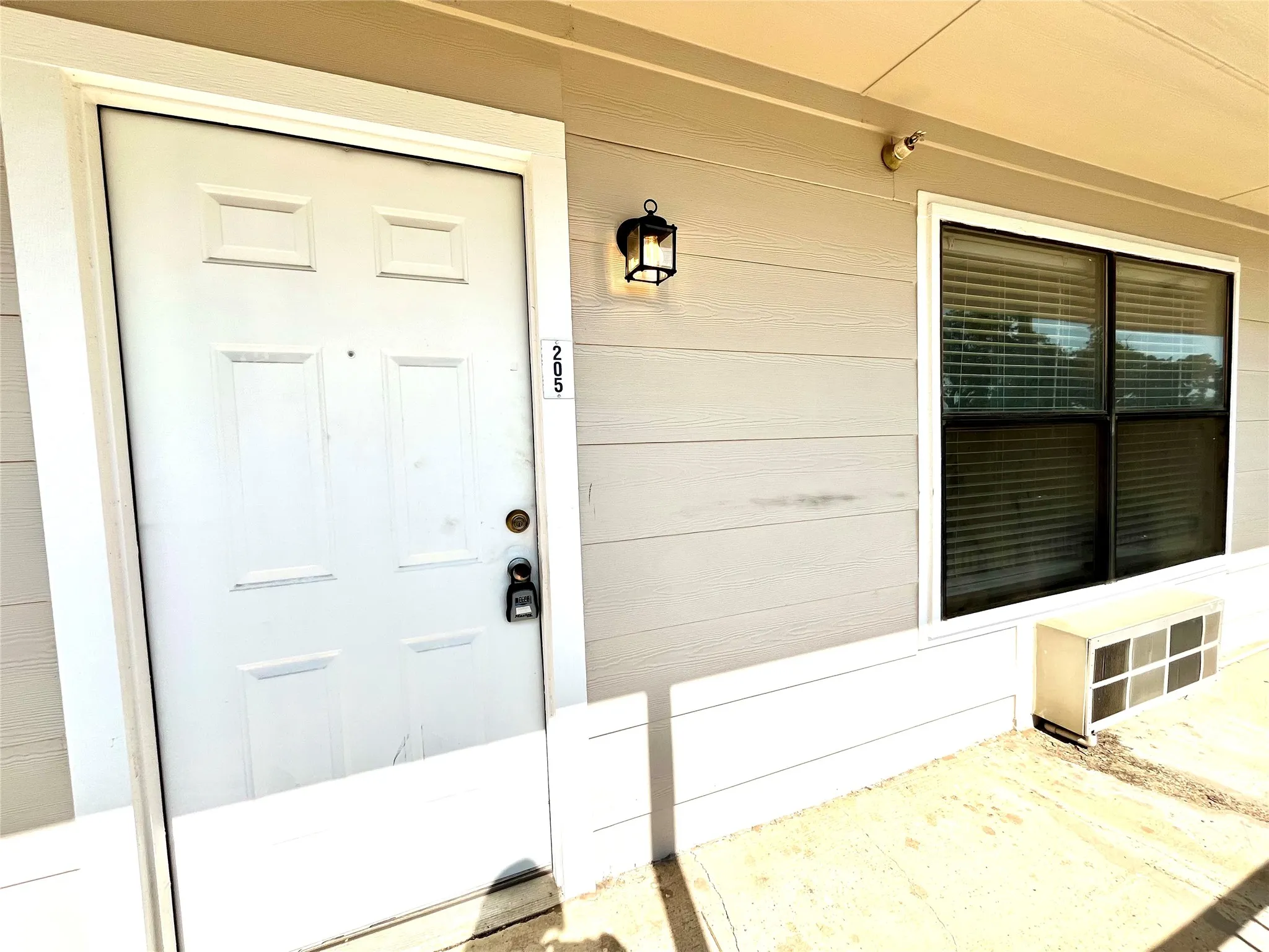 Clean unit entrance featuring a secure door and neutral siding.