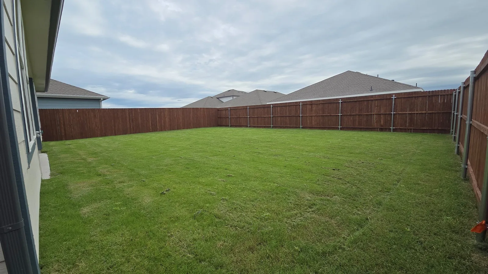 Expansive backyard featuring a lush lawn and perimeter wood fencing