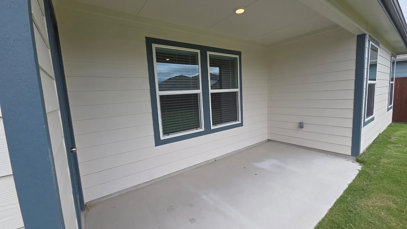 Covered patio with concrete flooring, recessed lighting, white horizontal siding, and dark trim windows