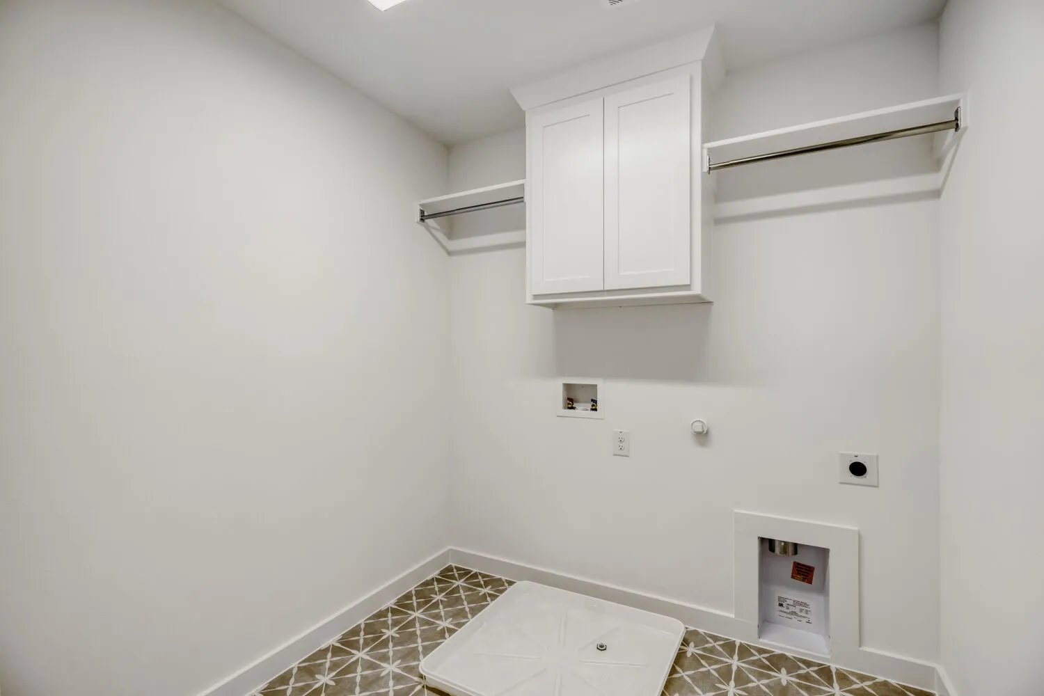Utility room featuring patterned floor tile, white wall cabinetry, and dual clothing rods
