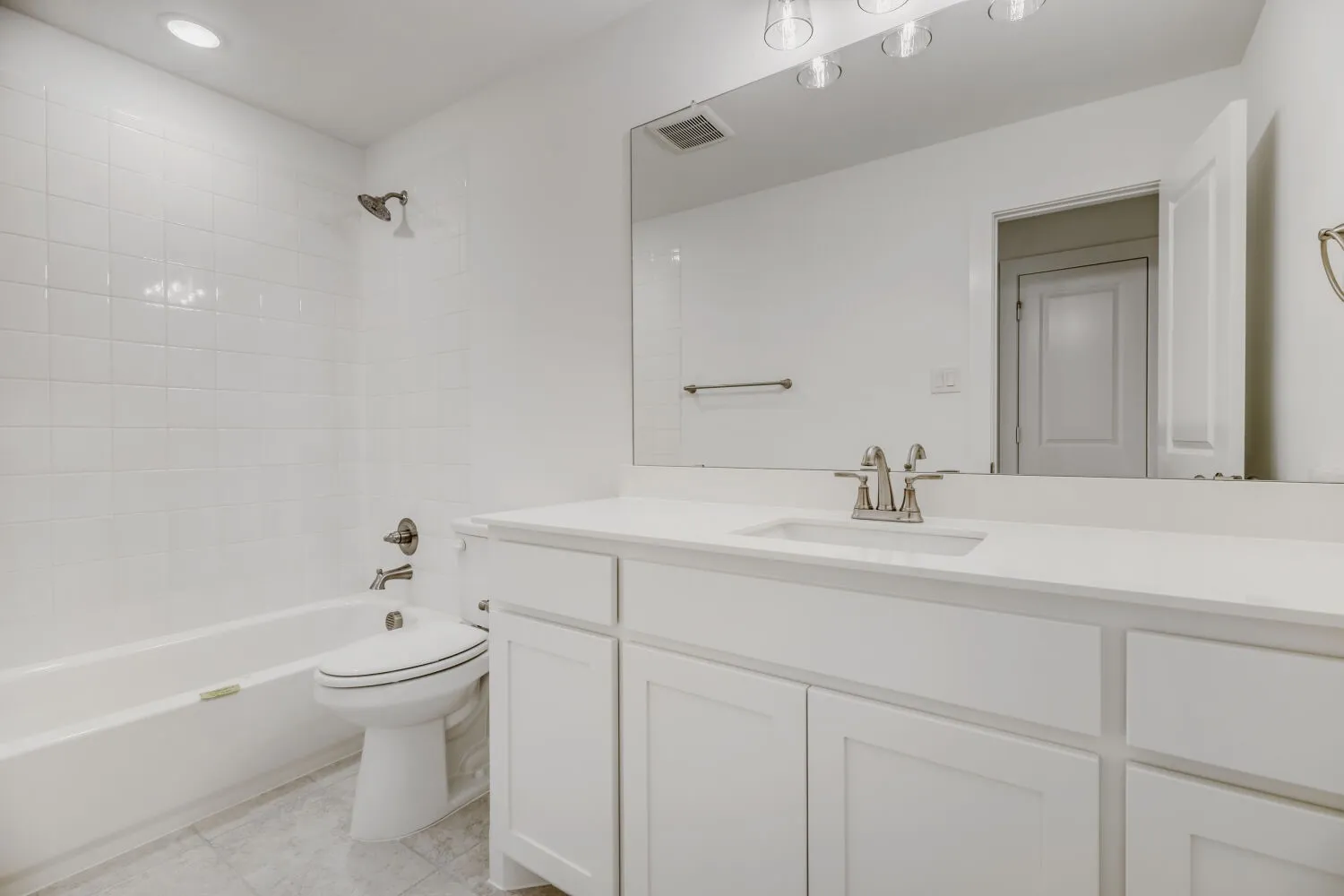 Bathroom featuring a white vanity with an integrated sink, brushed nickel faucet, and a large mirror