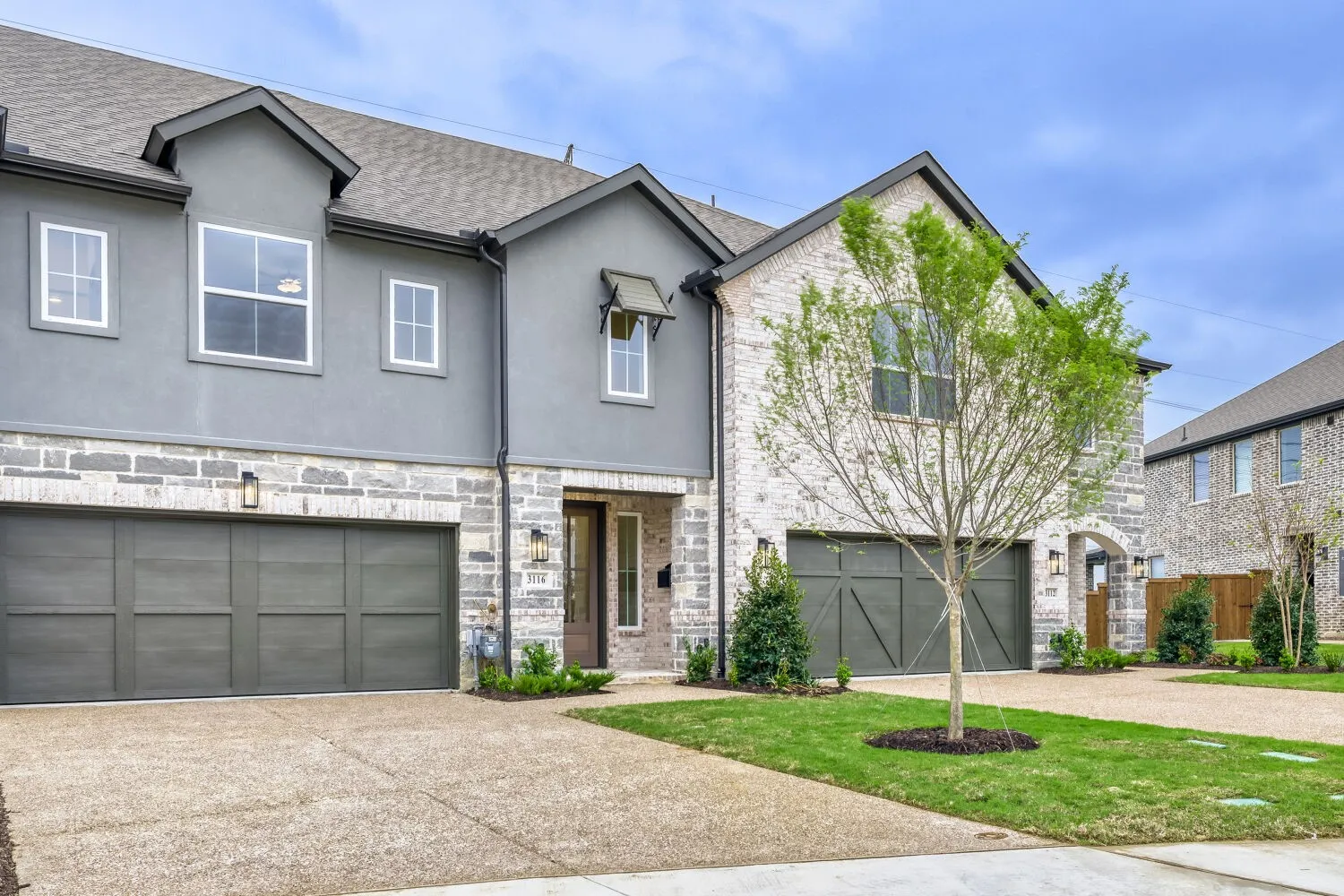 Gray stucco and brick facade with dark gray garage doors