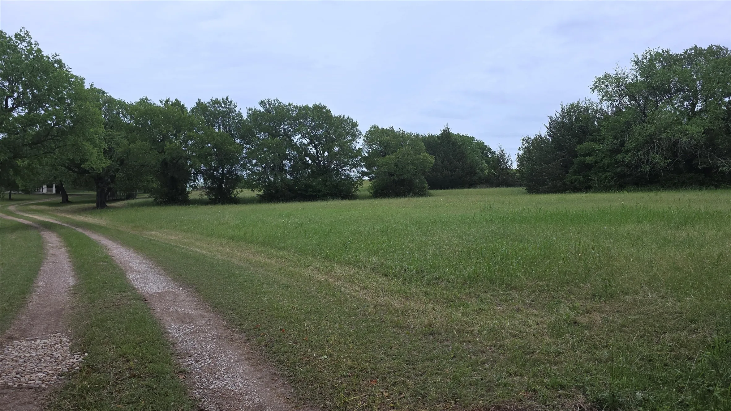 Enter the gate and a9 gravel drive extends to the house, mature trees, and open fields