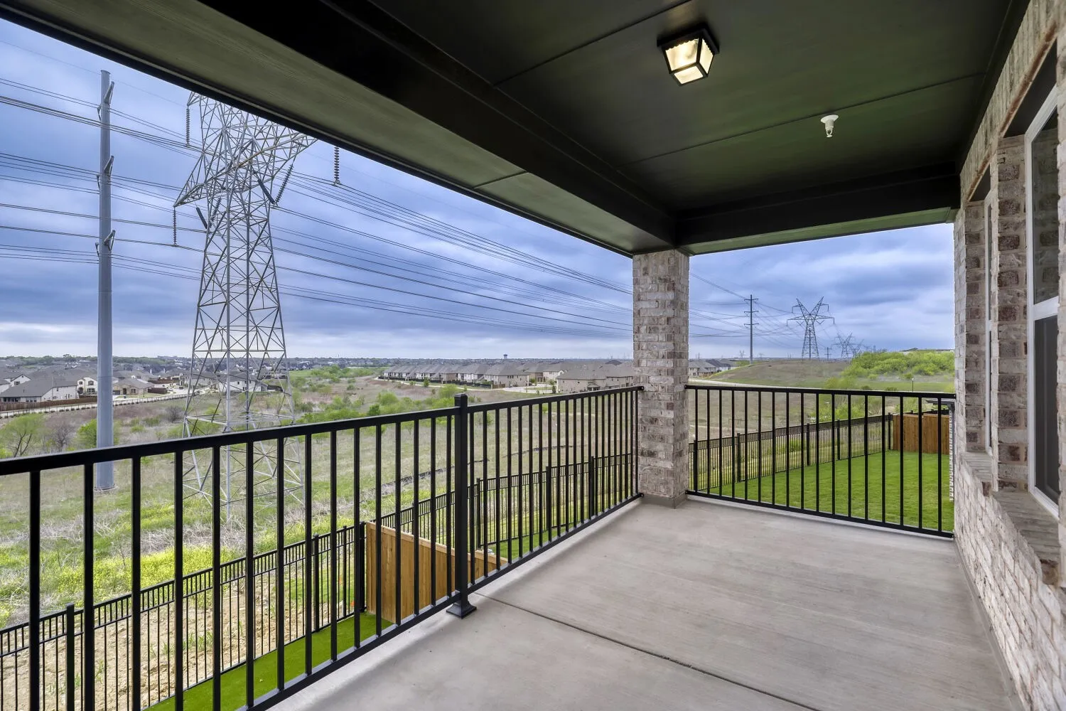 Covered balcony featuring concrete flooring and a black metal railing