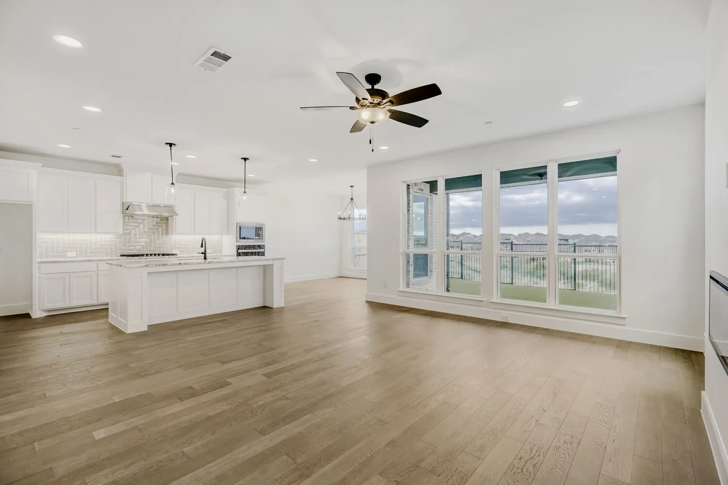 Open-concept living area featuring wood-finish flooring, recessed lighting, and a ceiling fan