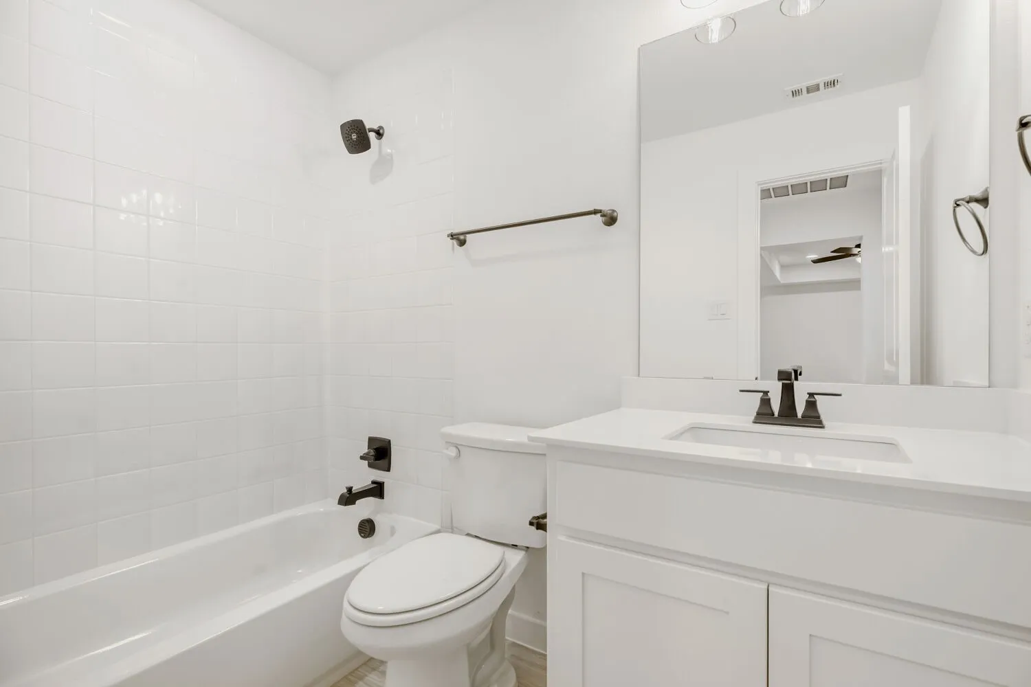 Bathroom featuring a white vanity with an integrated sink, dark bronze fixtures, and a spacious mirror