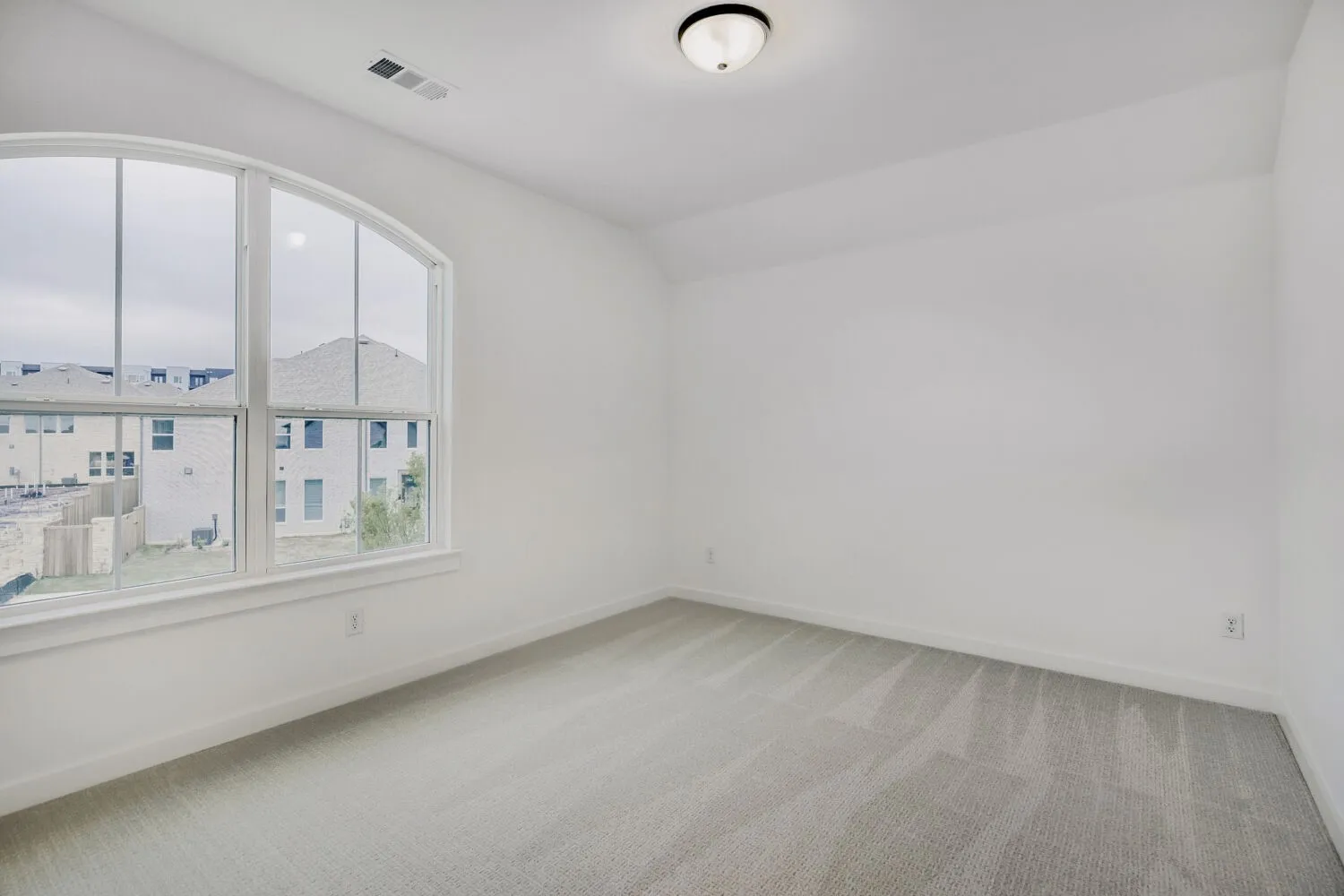 Room featuring a large arched window, light gray carpeting, white painted walls, and a flush-mount ceiling light