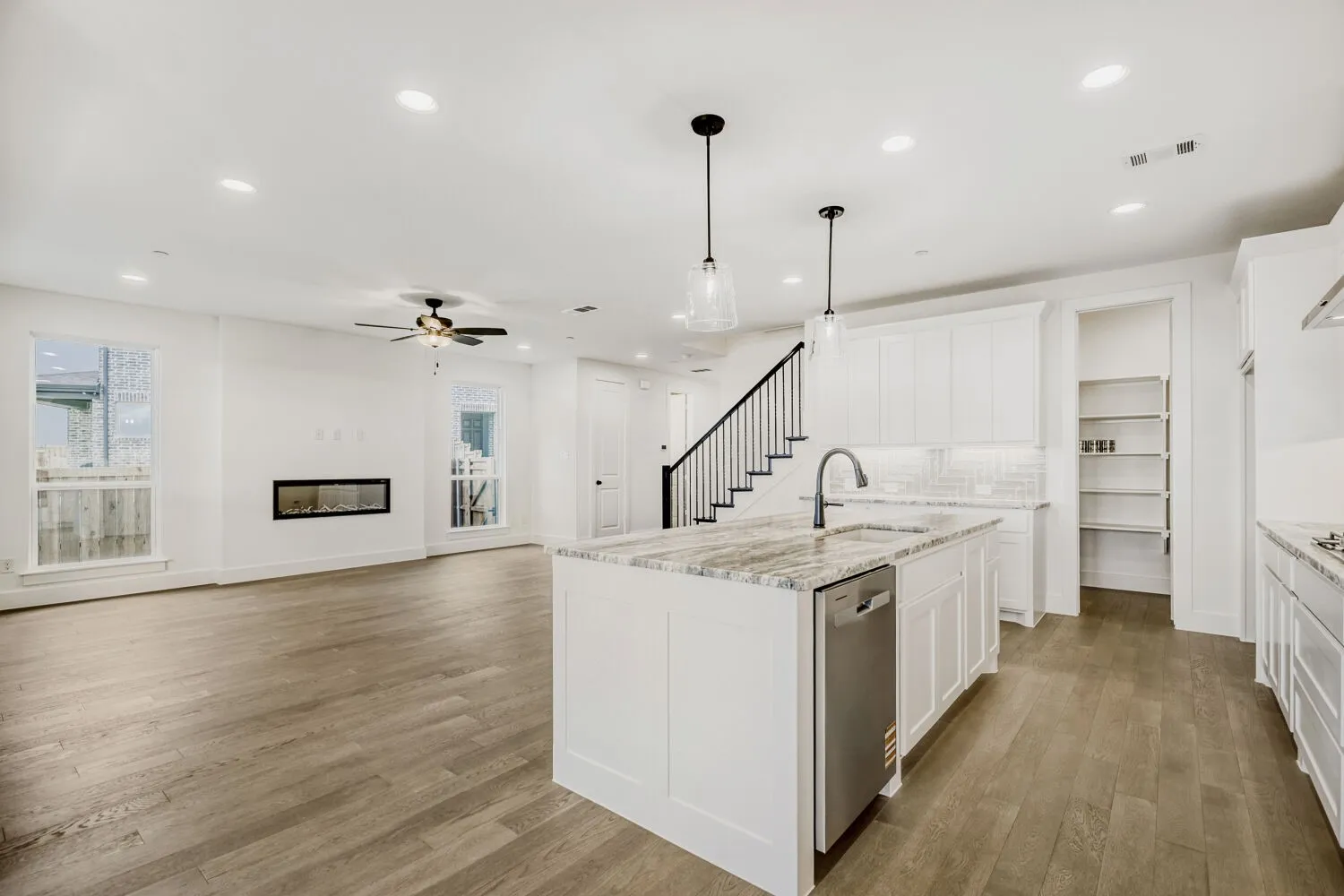 Open-concept living space with wood-finish flooring, a linear electric fireplace, and recessed lighting
