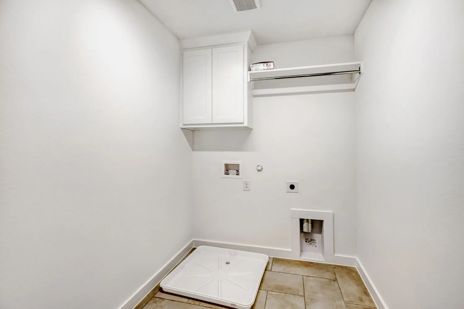 Dedicated utility space featuring white shaker-style cabinetry, a chrome hanging rod, and neutral tile flooring