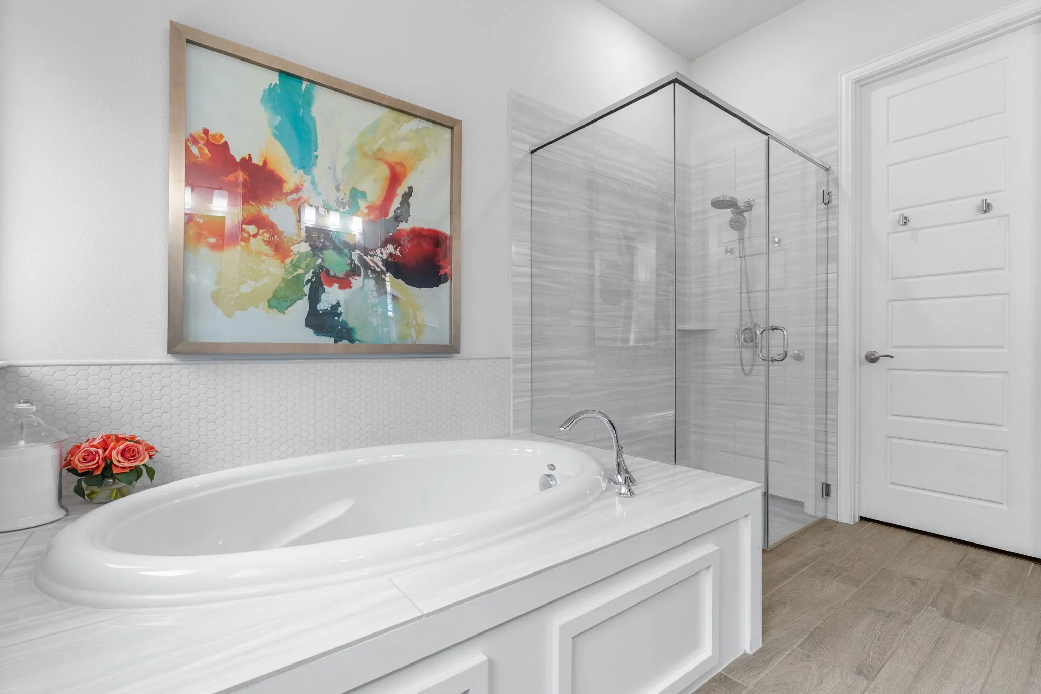 Well organized primary closet through the right door also has Mohawk wood flooring. Note the garden tub's decorative wall tile as well. Super clean!
