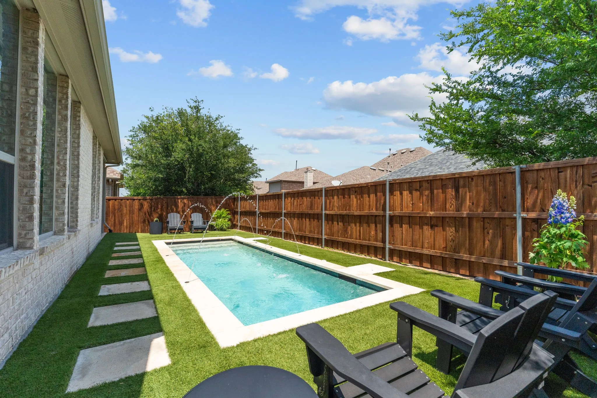 Other features of the swimming pool: eye-catching glass penny tile accents & a Dolphin pool cleaner for easy care. Note the recently stained board-on-board privacy fence.