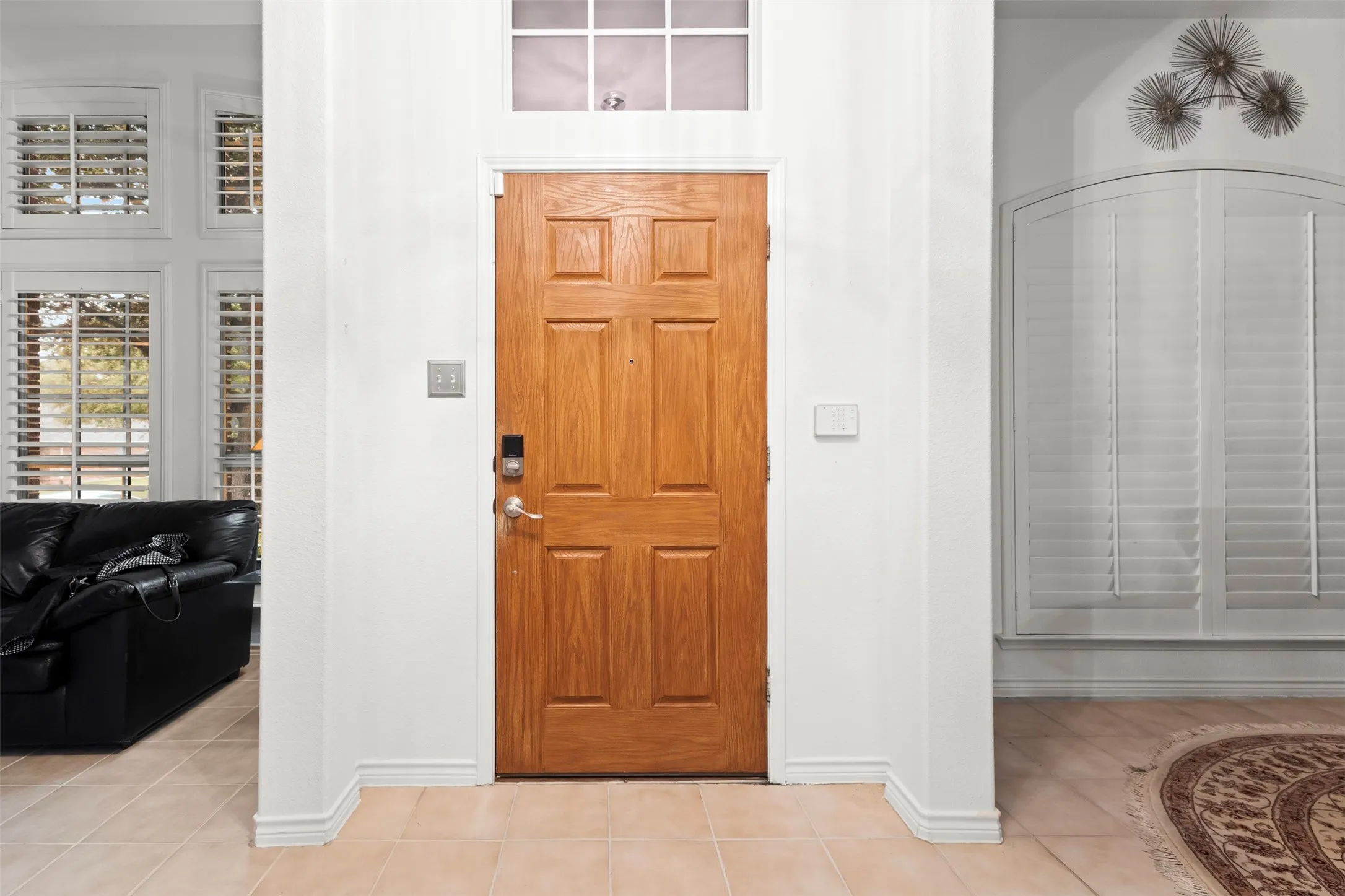 Wood-paneled entry door with transom window and sidelight framing