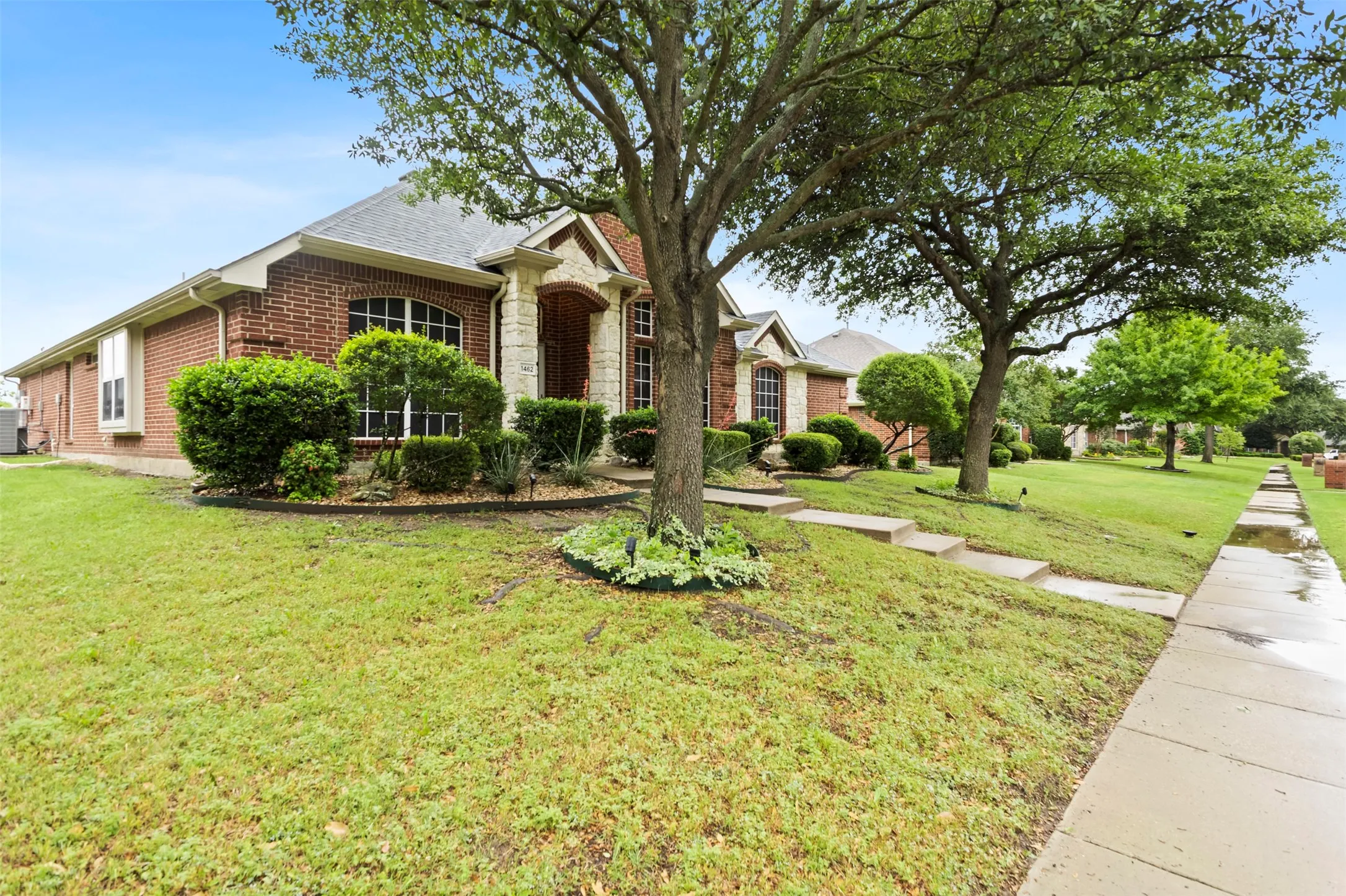 Brick exterior with stone accents and a mature tree-lined front yard