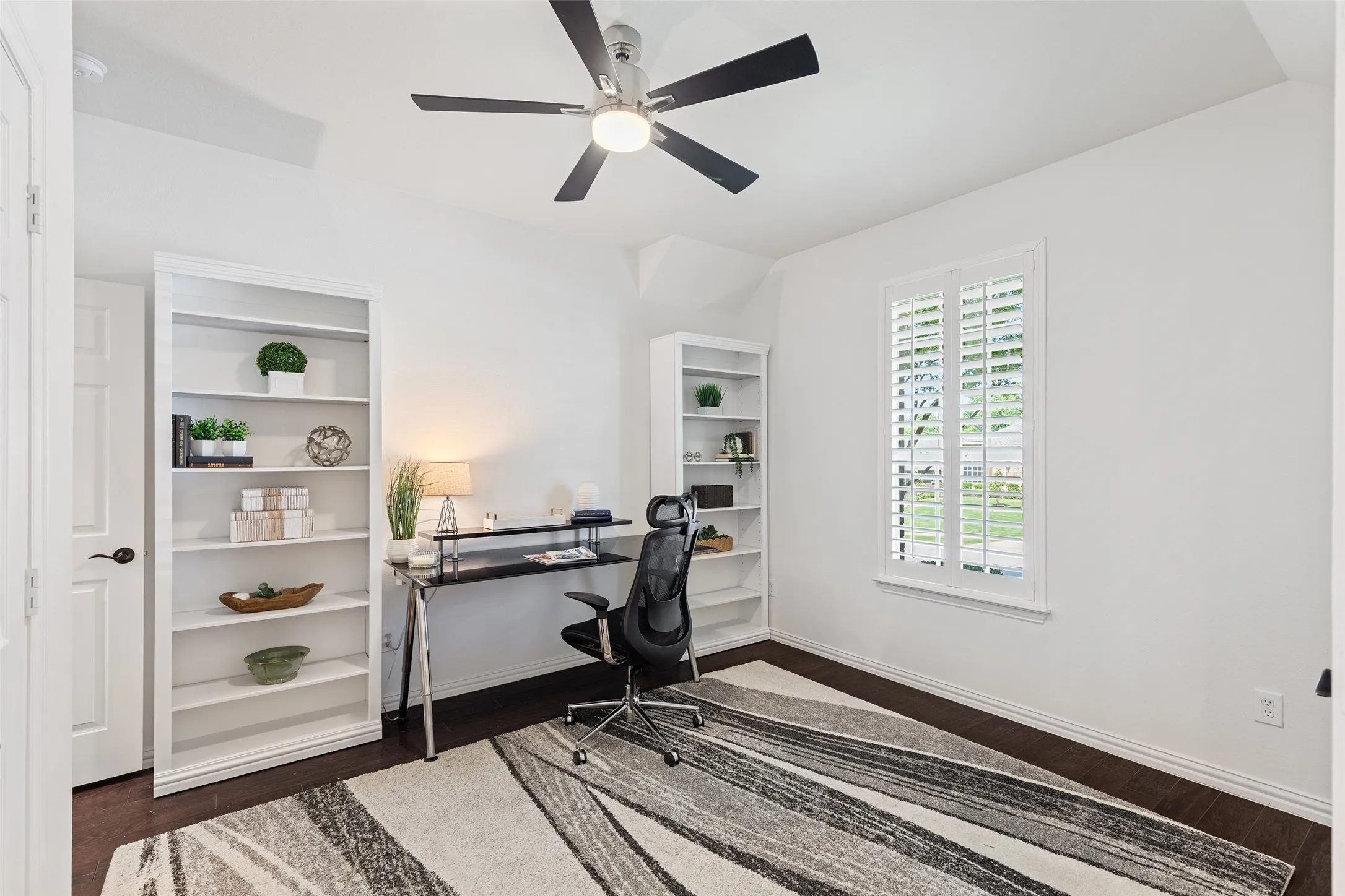 Dedicated home office with plantation shutters and built-in shelving for added functionality.