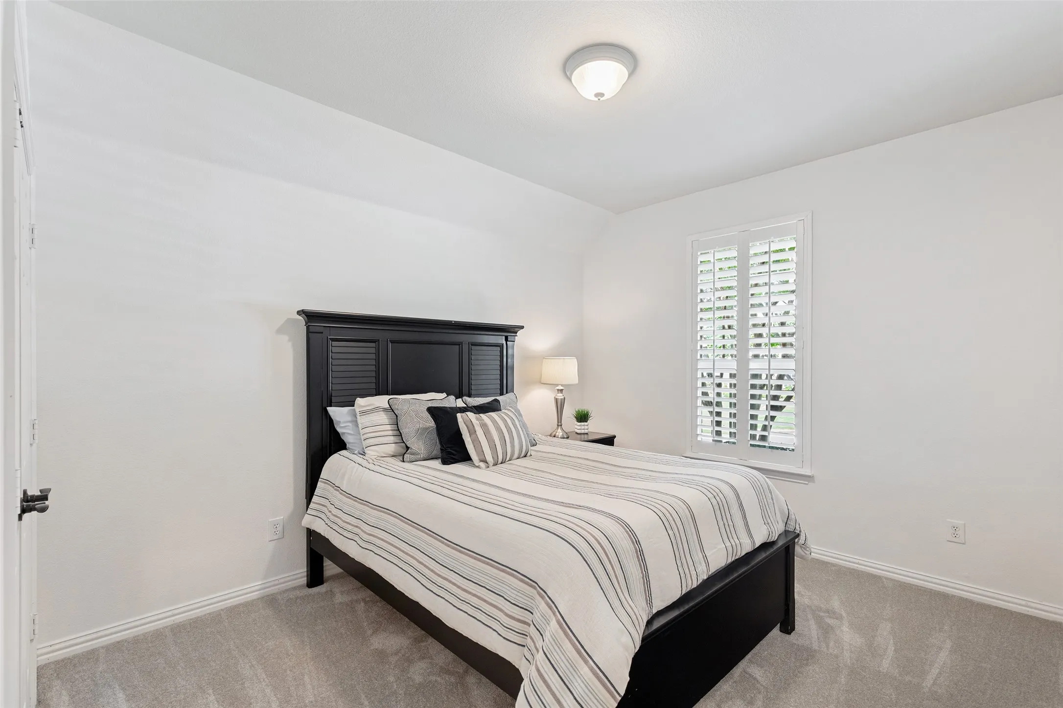 Comfortable secondary bedroom with vaulted ceiling and soft natural light.