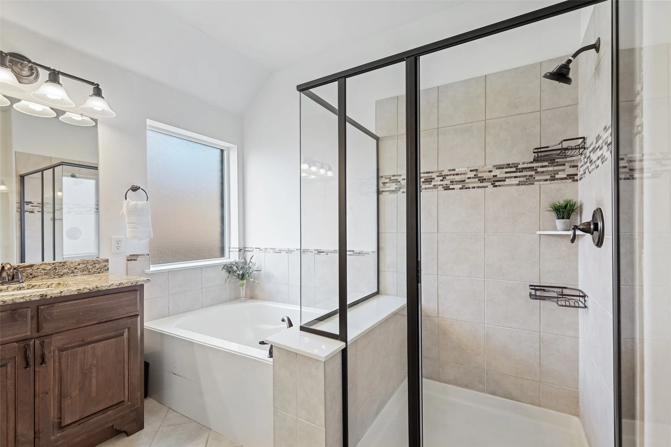 Elegant owner’s bath featuring dual vanities, framed glass shower, and soaking tub.