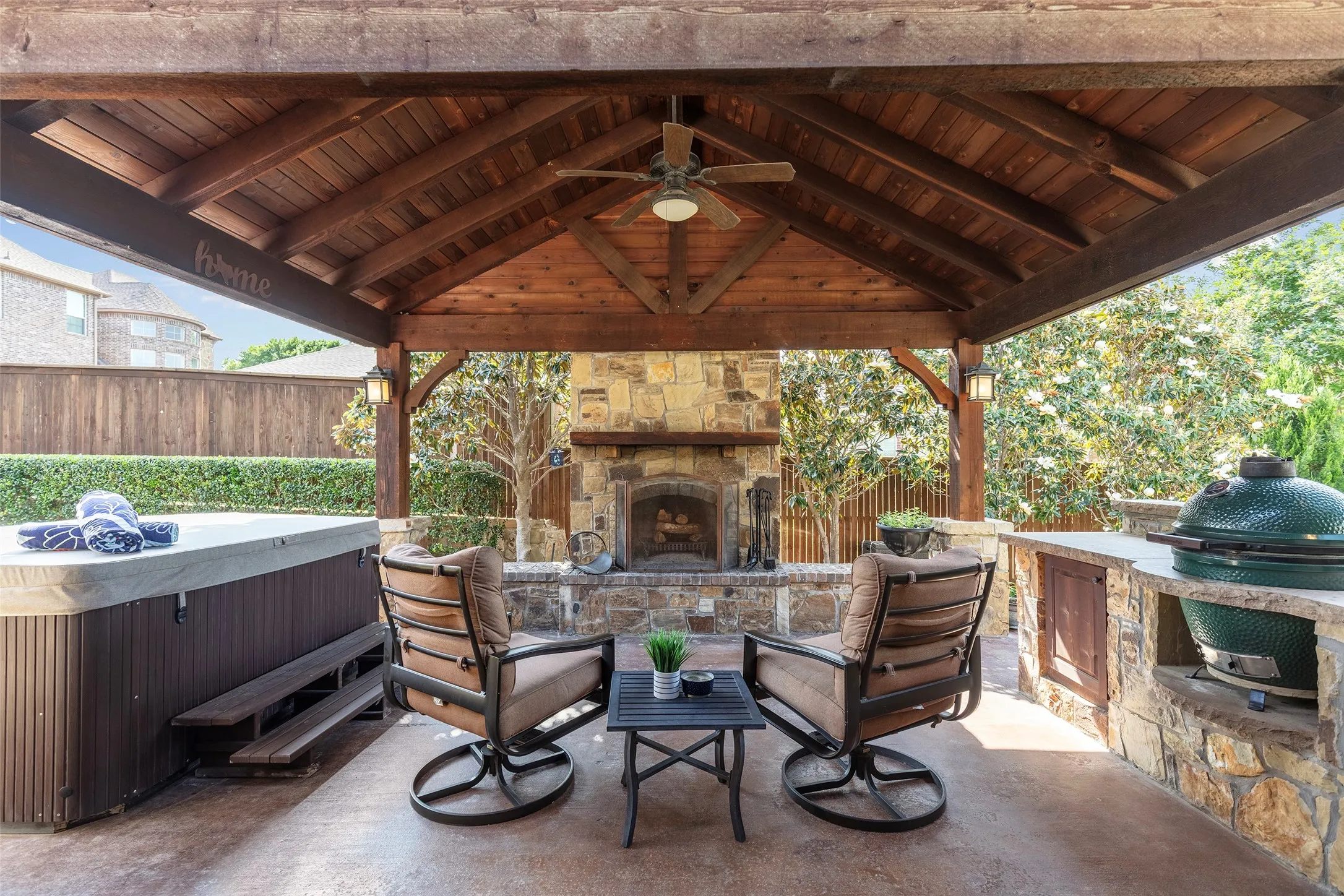 Covered outdoor living with a vaulted wood-beam ceiling, stone fireplace, and inviting seating area designed for year-round relaxation and entertaining.