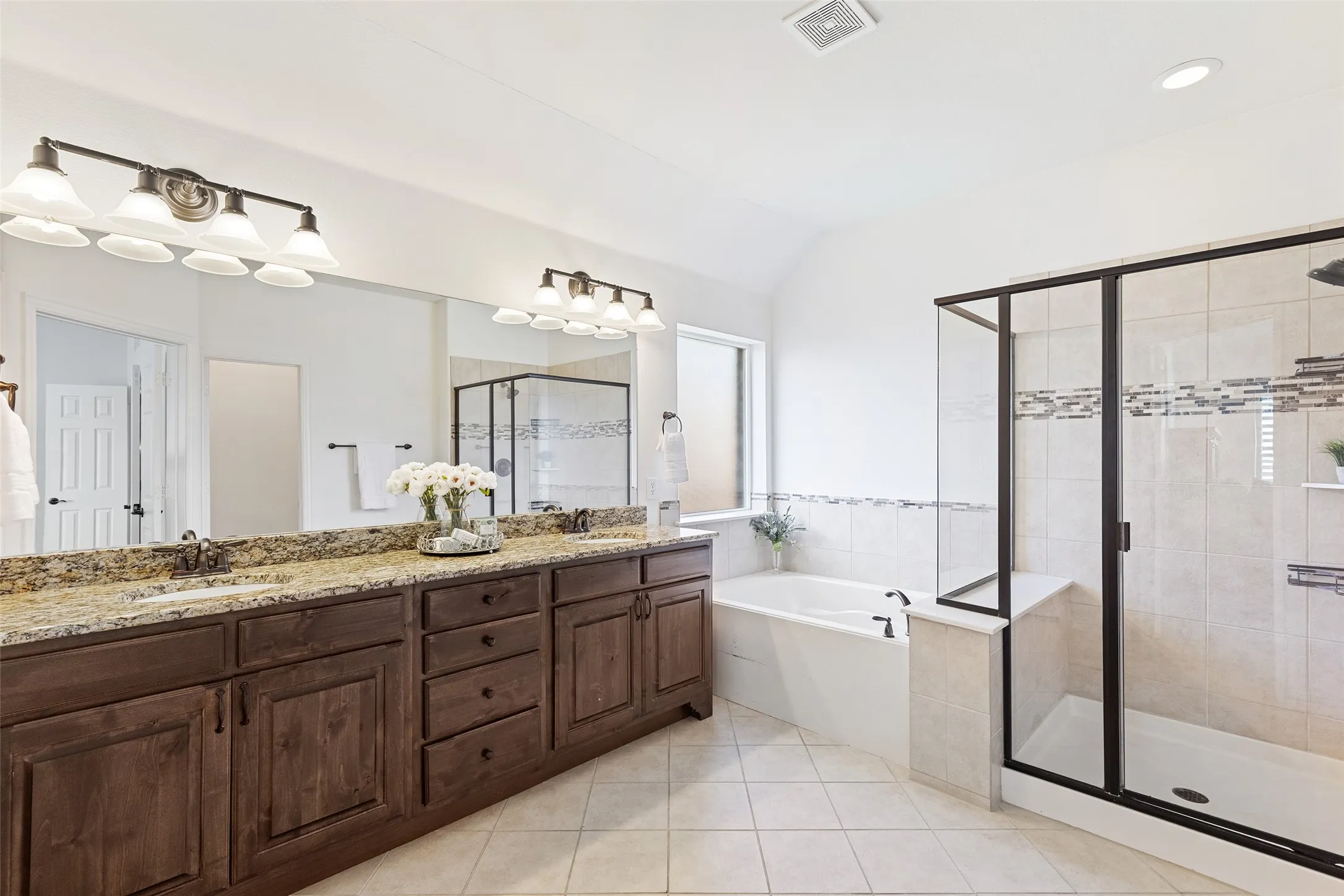 Spa-inspired primary bath with soaking tub, oversized shower, and granite vanity.