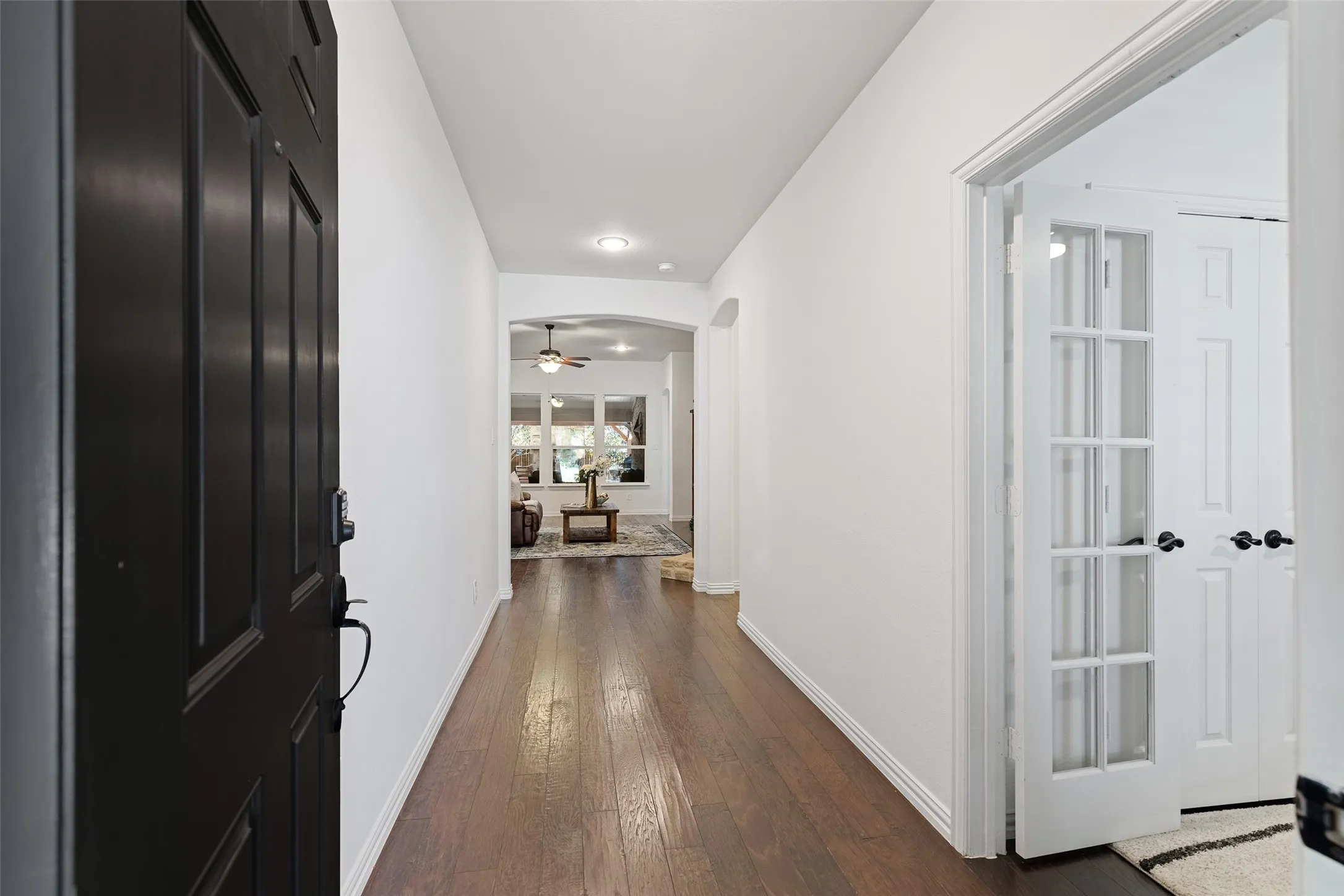 Welcoming entry hallway with wood floors and private office access through French doors.
