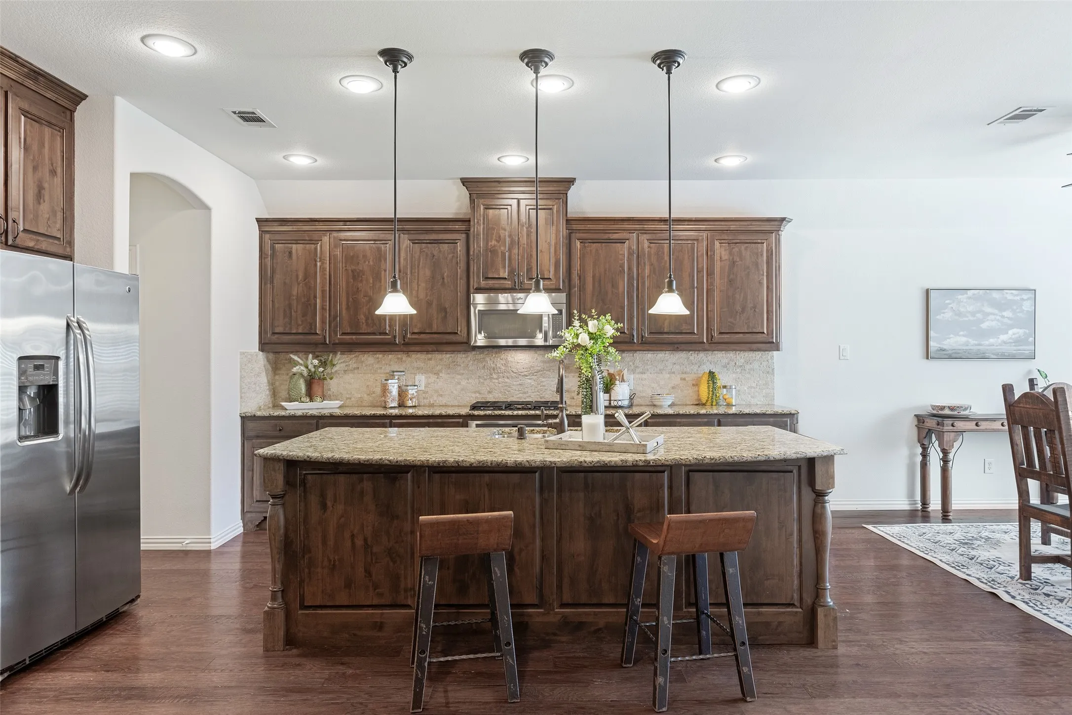 Warm custom cabinetry paired with expansive counters and casual bar seating.