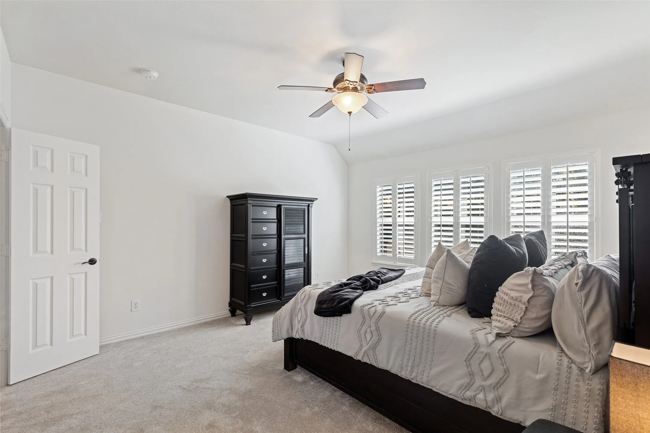 Private primary suite with sitting area, plantation shutters, and calming natural light.
