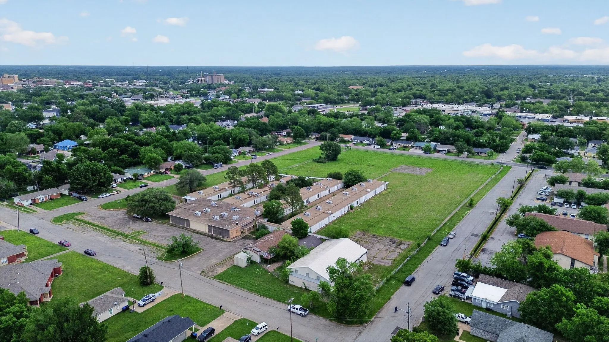 Aerial perspective showcasing a parcel of land with existing structures, surrounded by residential properties and mature trees