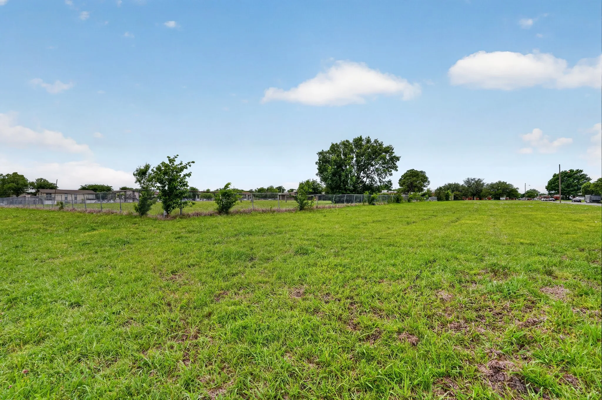Expansive open lot featuring a clear, level terrain and established perimeter fencing