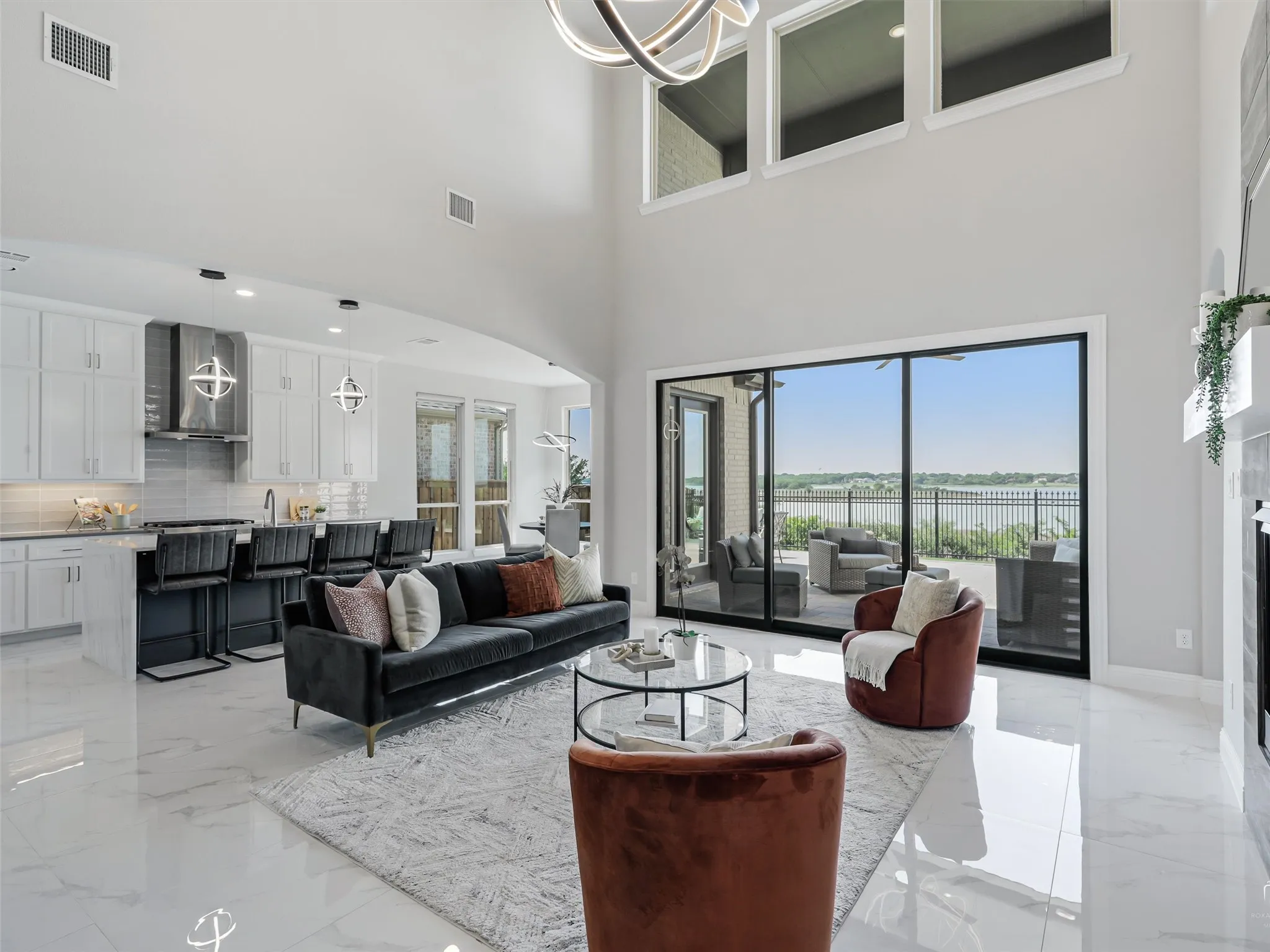 Open-concept living space featuring high ceilings, large format tile flooring, and a linear gas fireplace