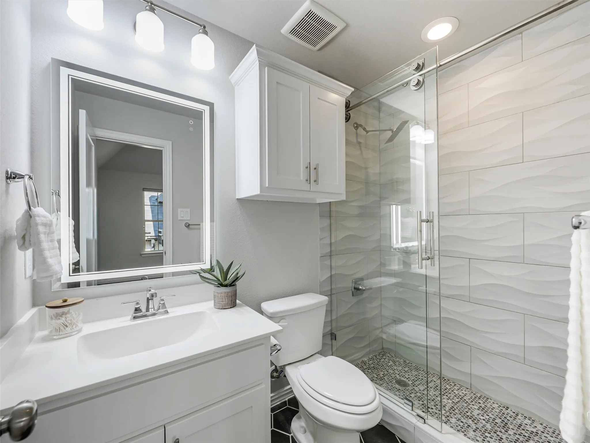 Walk-in shower with textured subway tile surround and pebble flooring